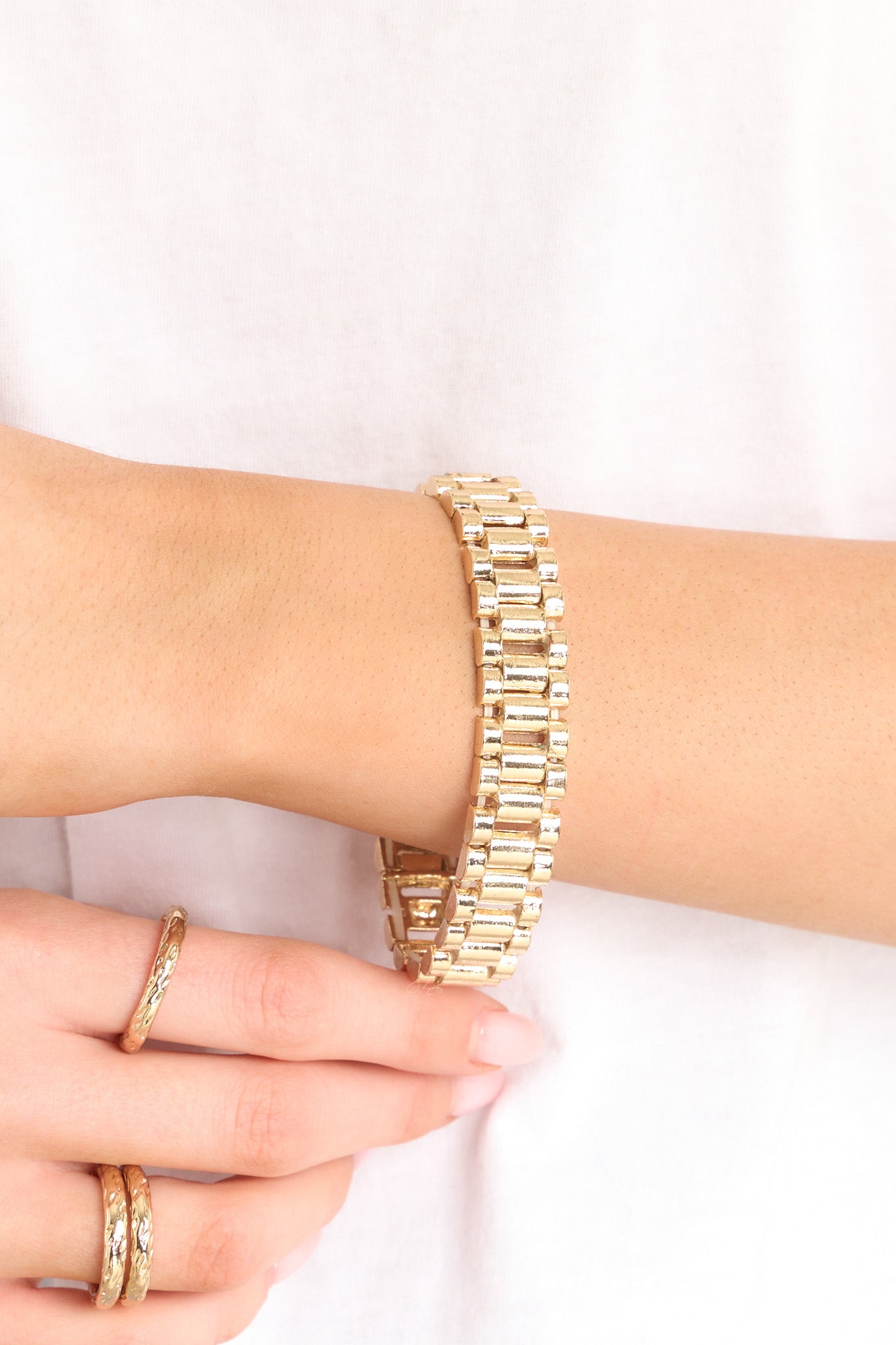 This gold bracelet features gold hardware, watch style band, stretch band, and a slip-on style.