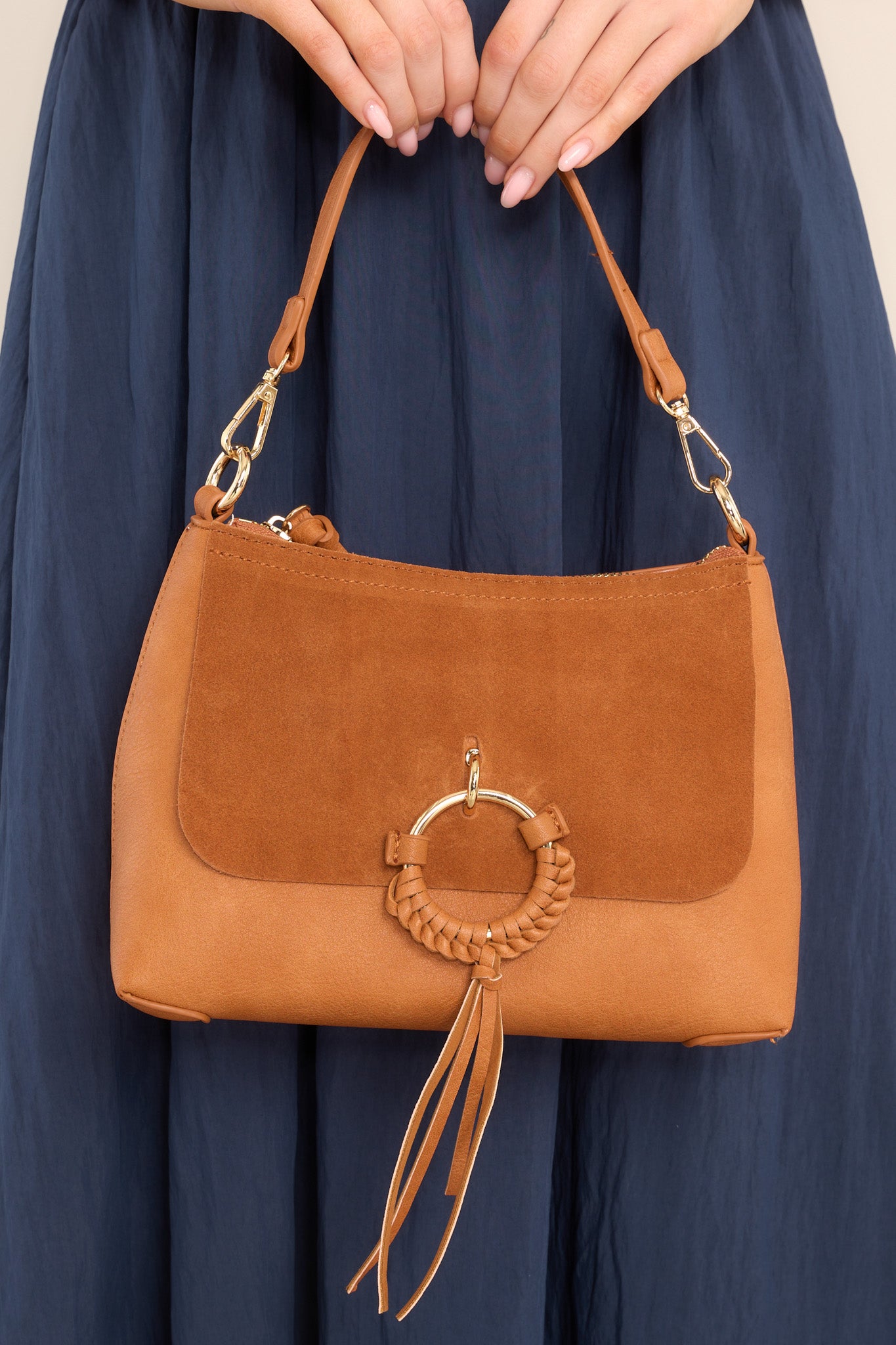 This tan bag features gold hardware, zipper closure, comes with two detachable straps (one short & one long), has mixed textures, and a statement ring in the front.