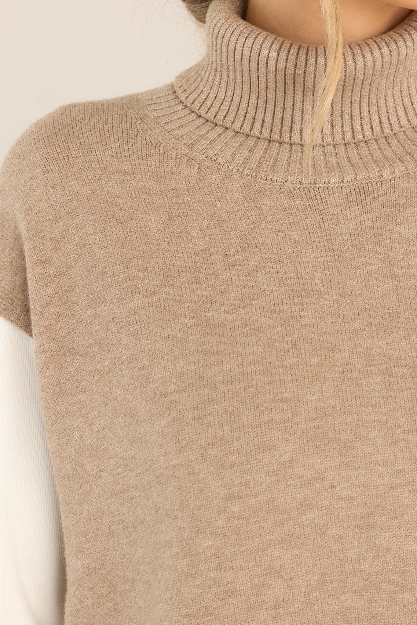 Close up view of this sweater vest that features a relaxed-fit, turtleneck, rib-knit fabric throughout, slits at sides of hem and longer at back.