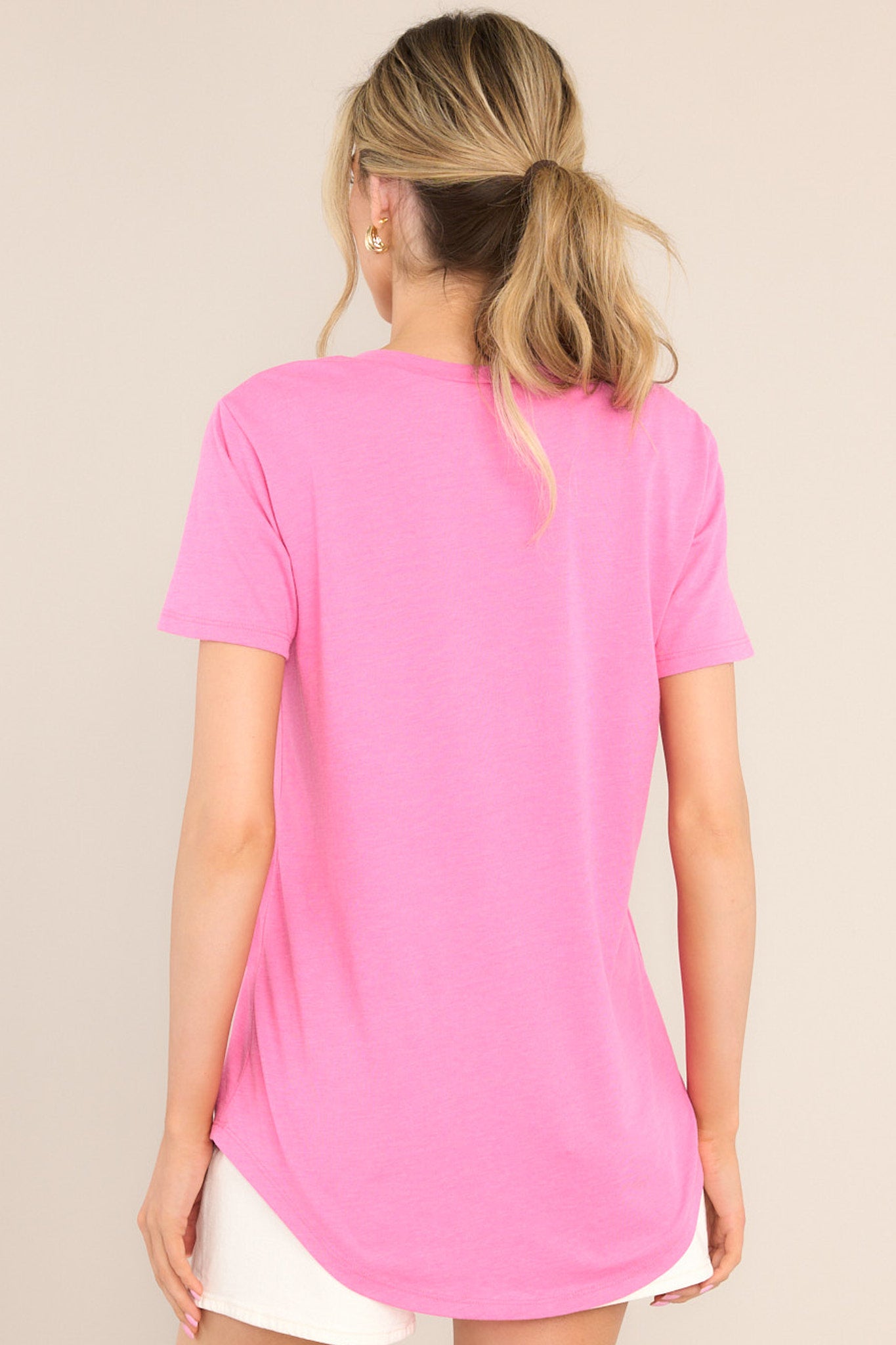 Back view of this tee that features a v-neckline, a slouched breast pocket, a scooped hemline, and short sleeves.