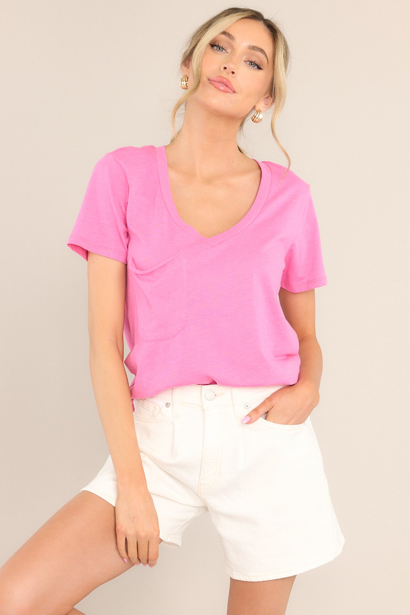 Front view of this tee that features a v-neckline, a slouched breast pocket, a scooped hemline, and short sleeves.