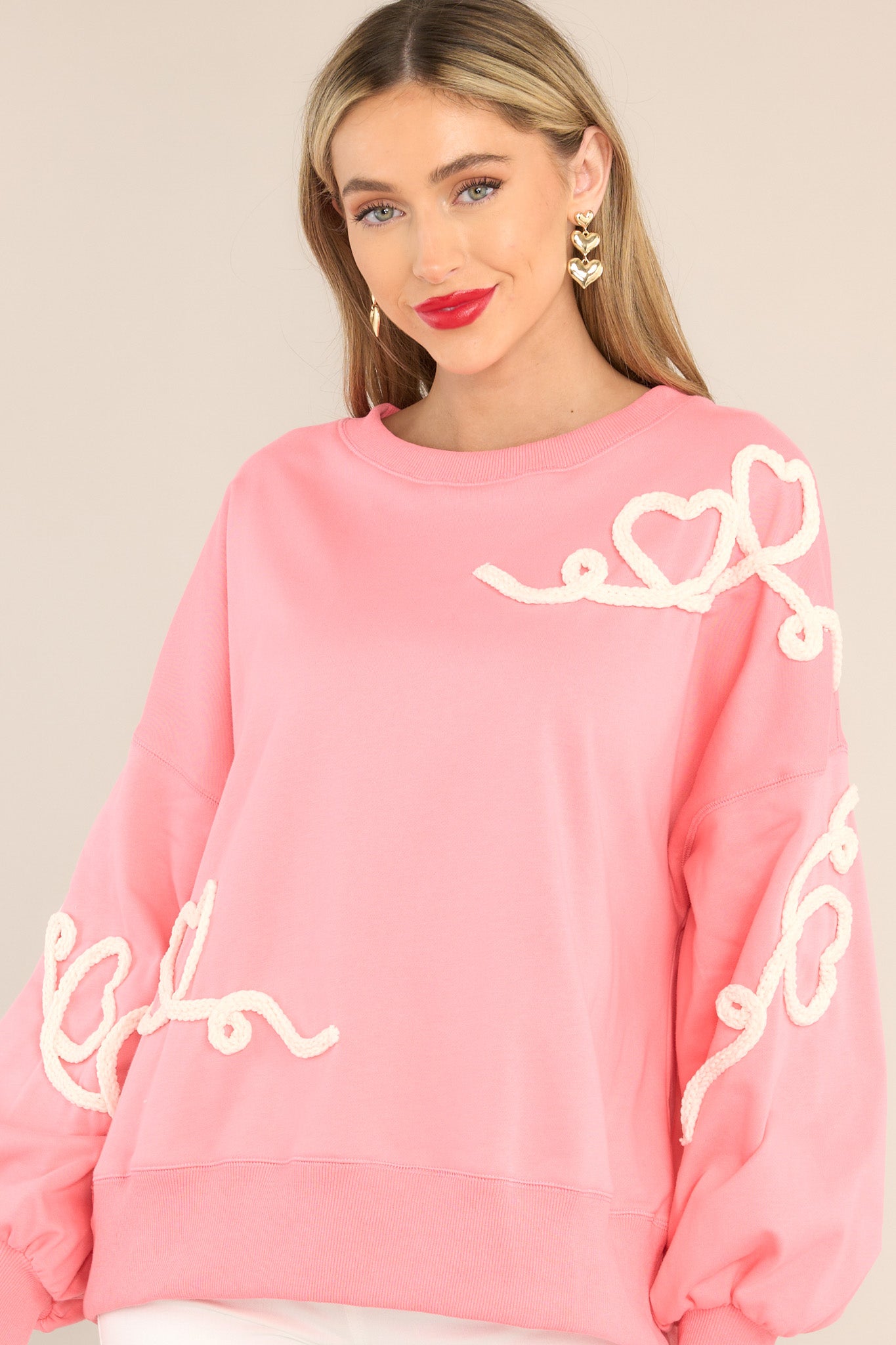 Front view of this sweatshirt that features a crew neckline, dropped shoulders, textured whimsical heart detailing, ribbed cuffed bishop sleeves, and a ribbed hemline.