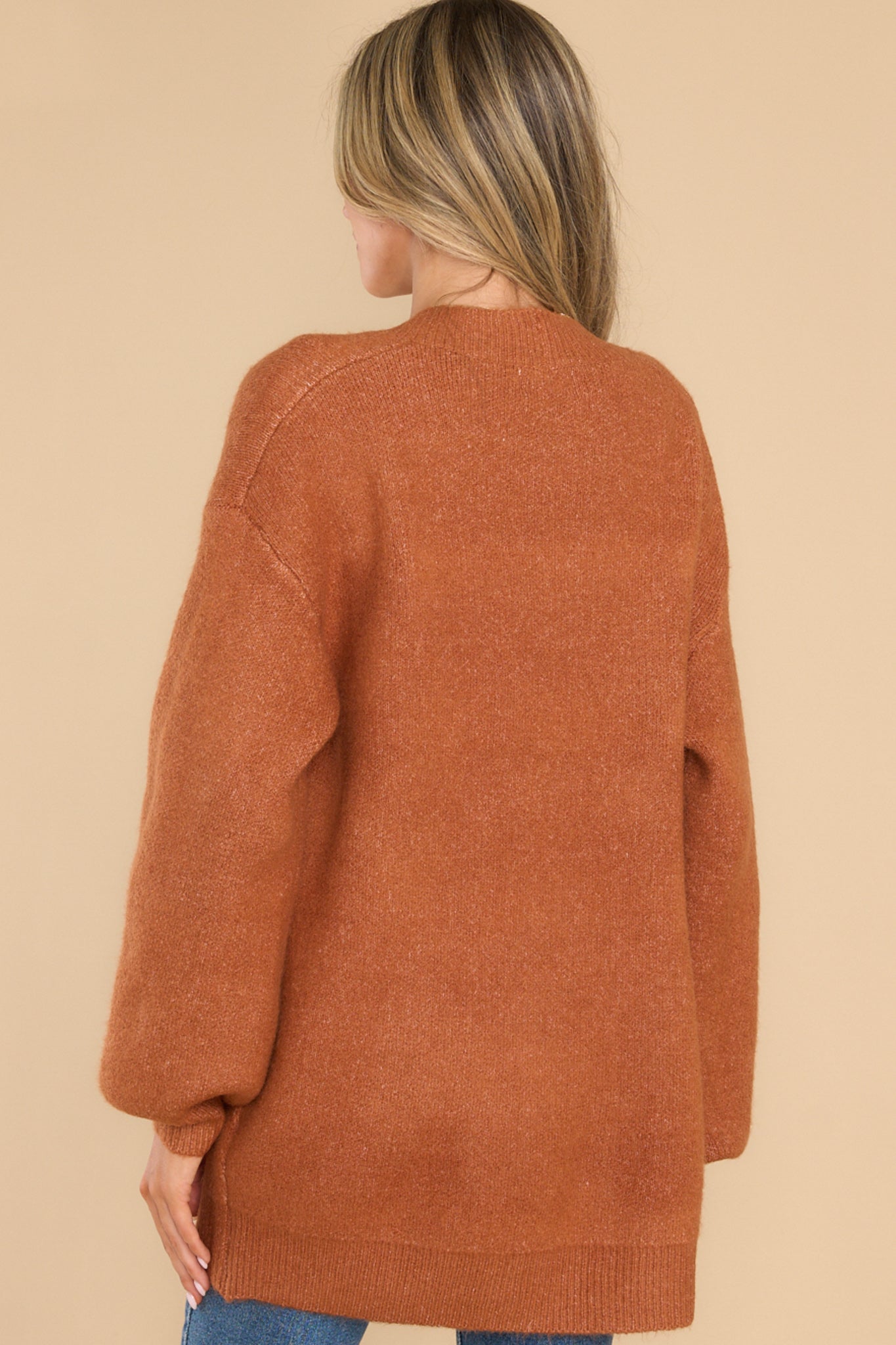 Back view of  this cardigan that features a v-neckline, functional buttons down the front, two front pockets, ribbed cuffs, and slight balloon sleeves.