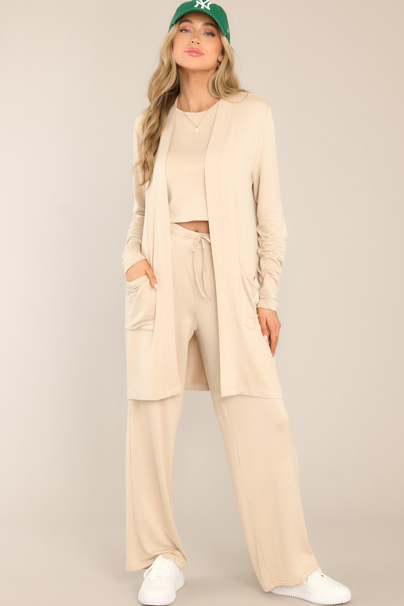 These beige pants feature a high waisted design, a self-tie drawstring, functional pockets, and a wide leg.