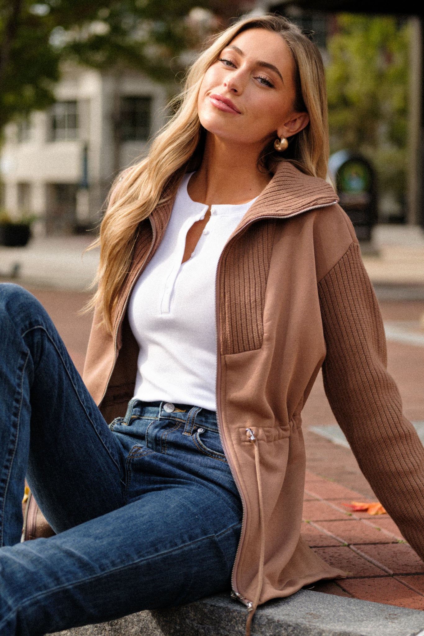 A mid-section view of the brown jacket, emphasizing the drawstring cinch waistband with silver accents and the texture of the contrasting fabrics.