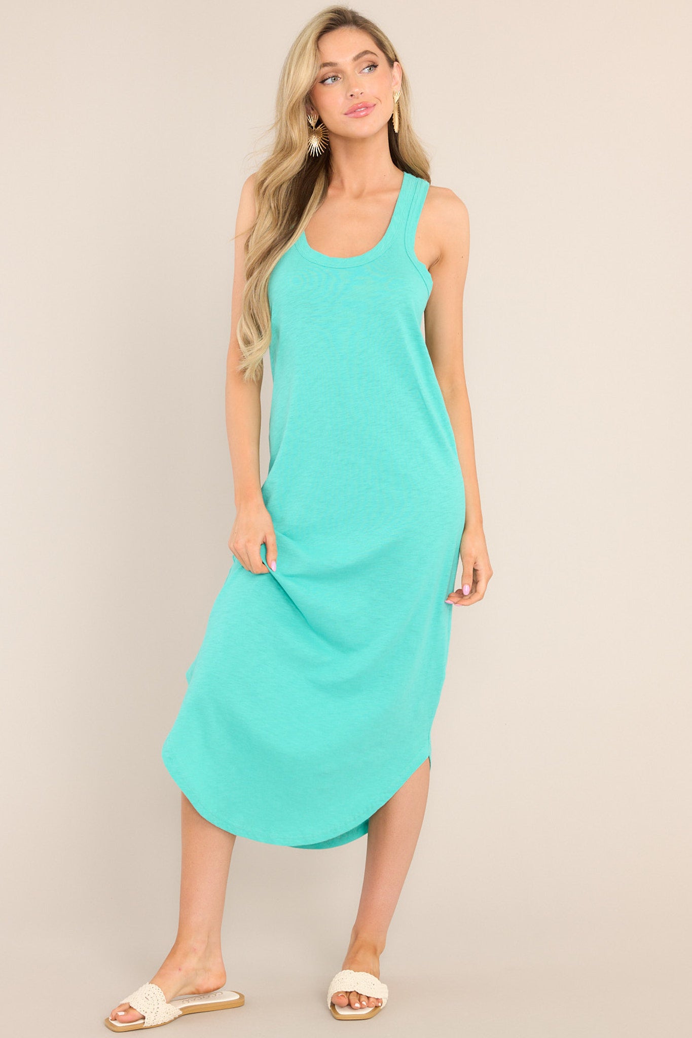 This green dress features a scoop neckline, a super soft material, a vibrant color, and a scooped hemline.