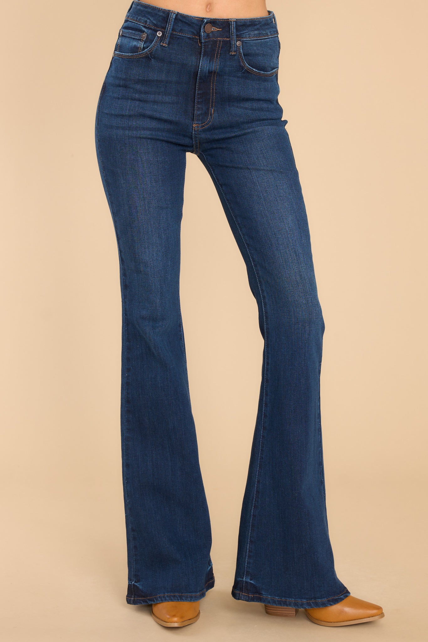 These dark wash jeans feature a high waist fit, belt loops, zipper and button closure, functional pockets, and a bell bottom flare.