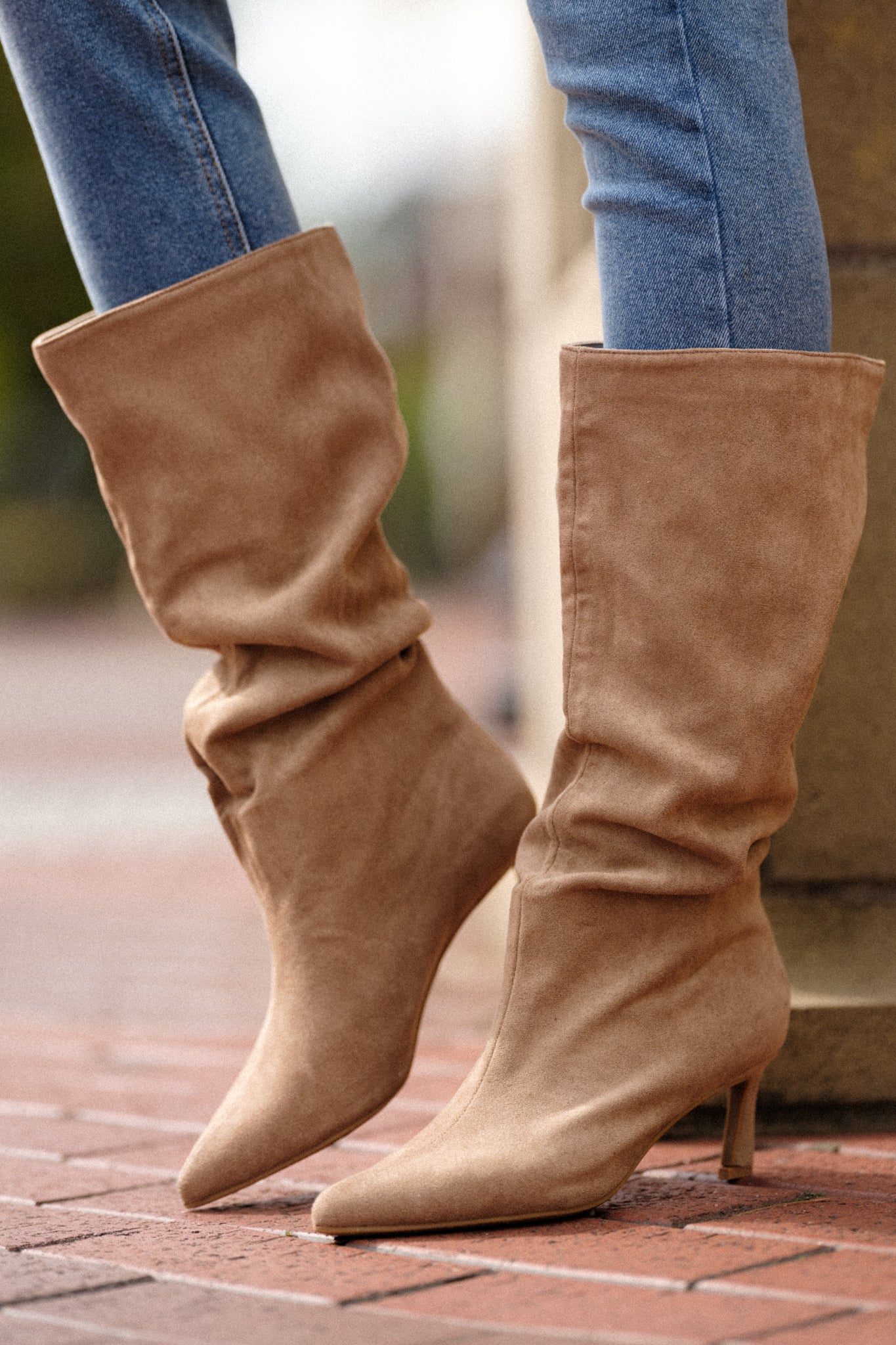 A cropped view of the brown boots, highlighting the pointed toe design and the rich texture of the soft brown suede material.