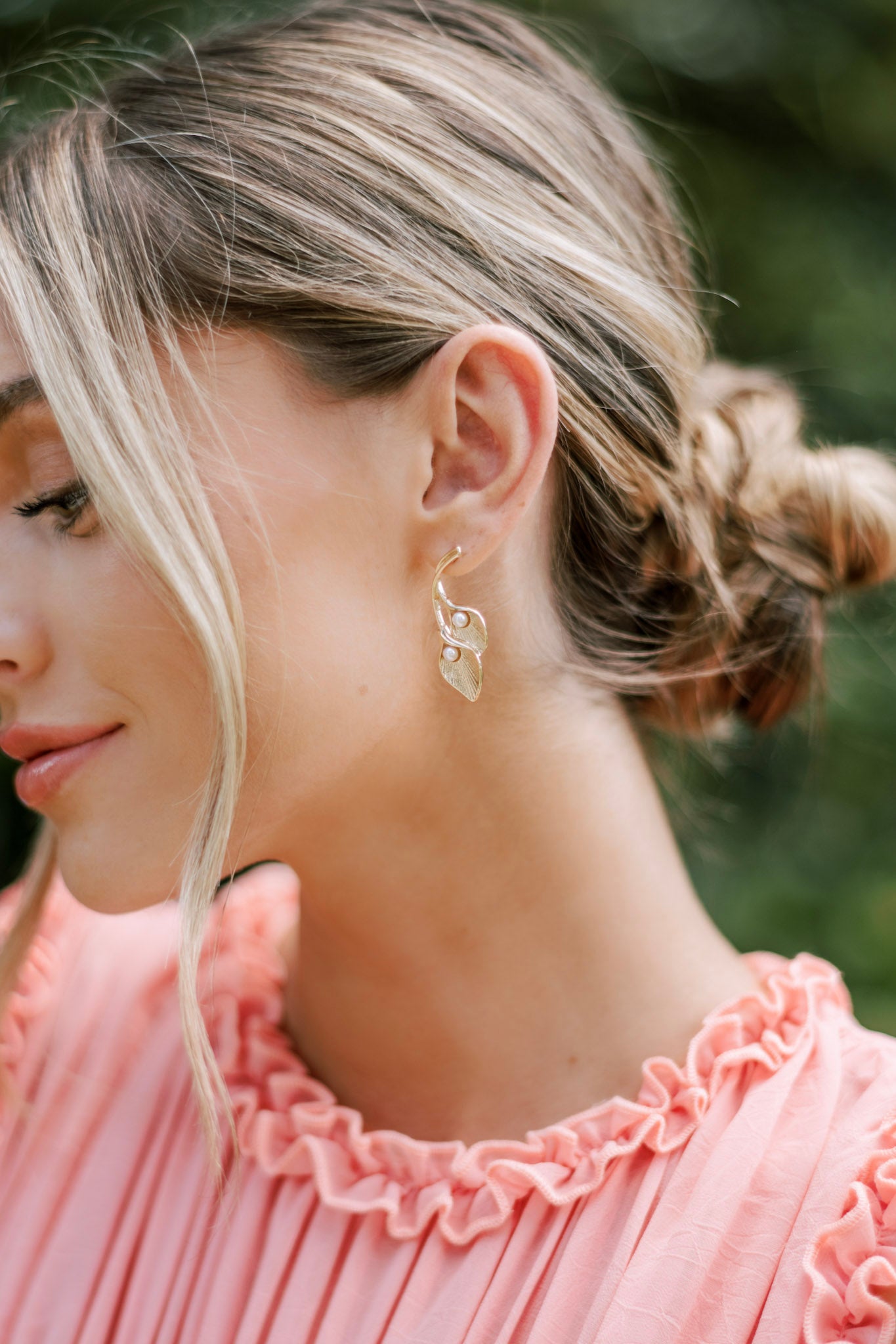 These earrings feature two leaf-like shapes with a textured surface, small ivory faux pearls, and secure post backings.