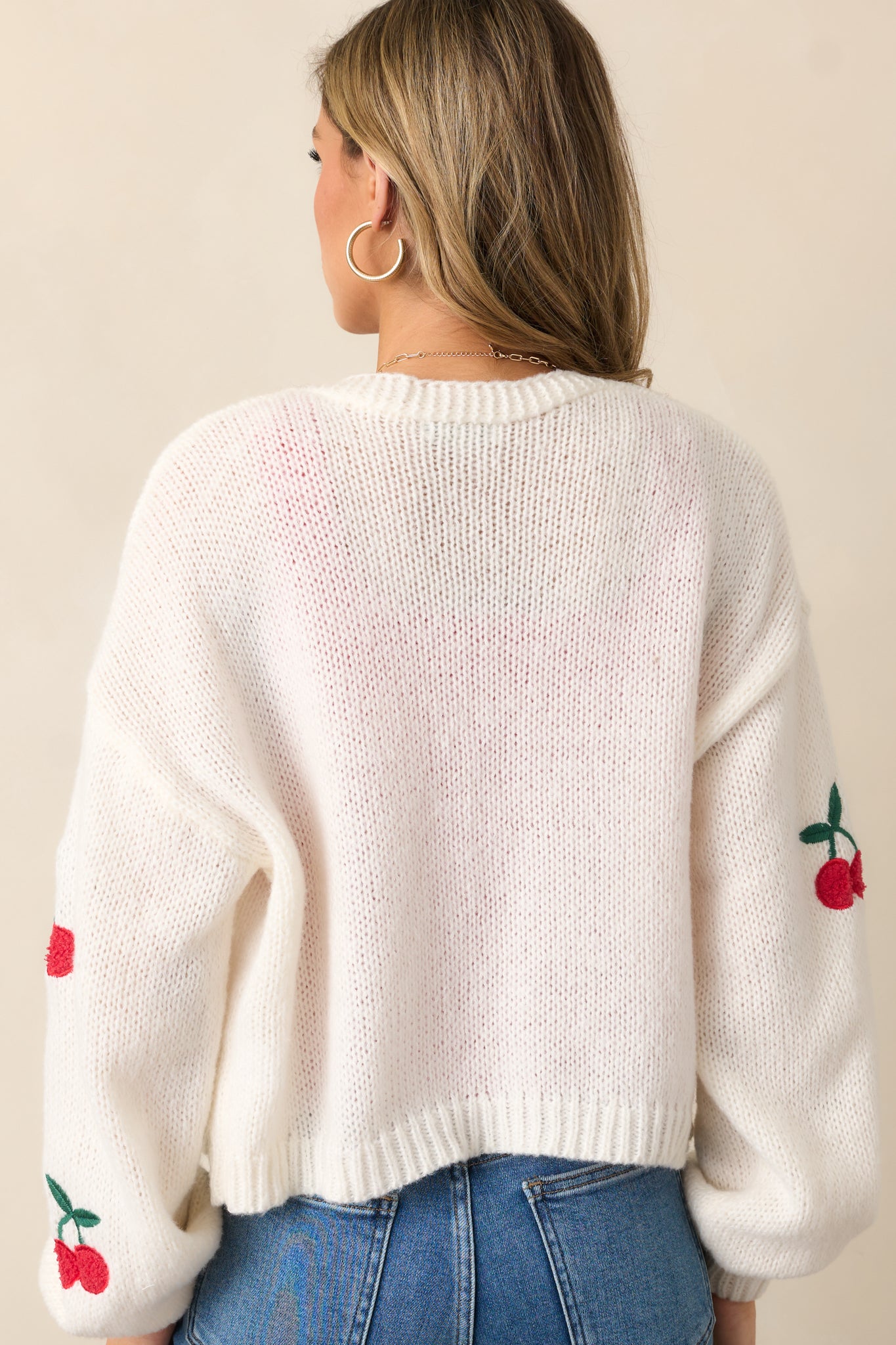 The back of the ivory cardigan, showcasing the uninterrupted ribbed texture and the long sleeve design.