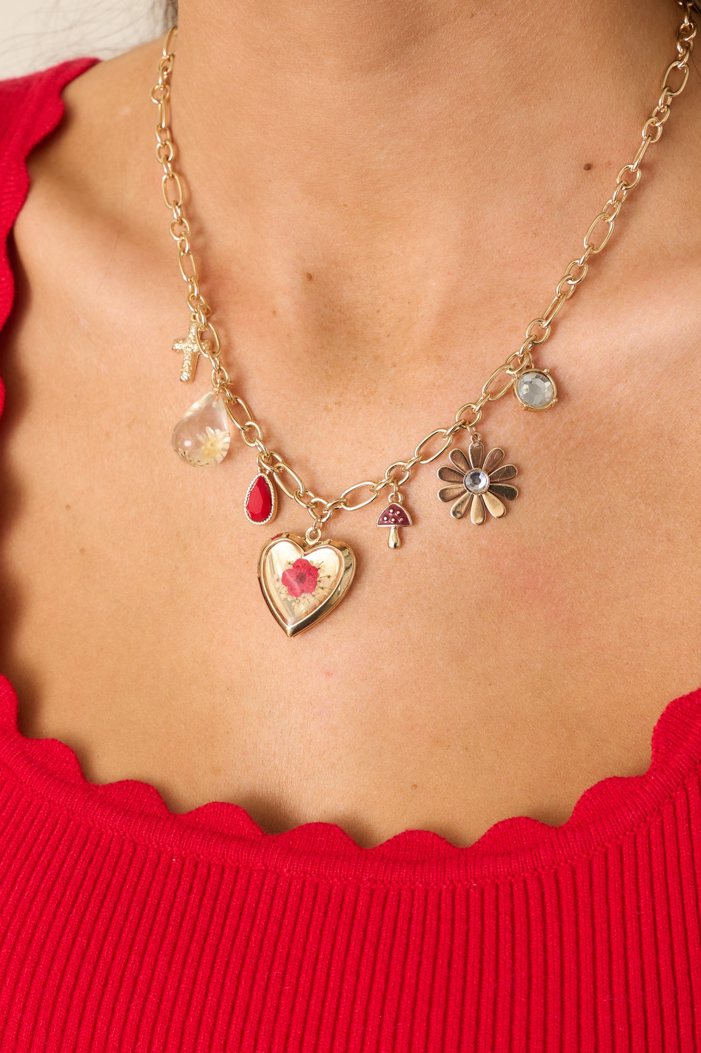 An up-close shot emphasizing the intricate details of the charms, including the heart locket, flower pendants, and the lobster claw closure on the rectangular gold chain.