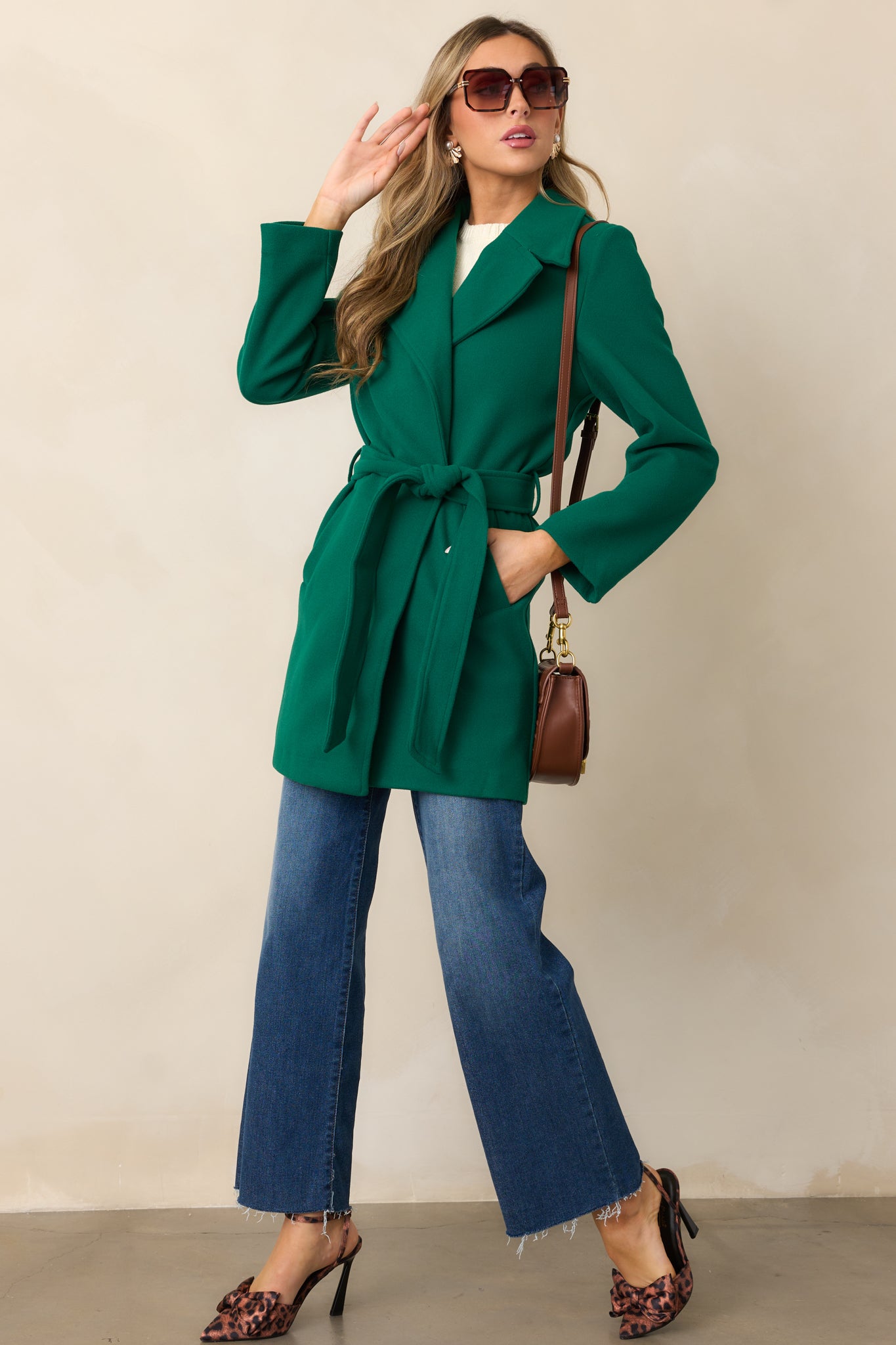 A view of the kelly green coat from head to toe, showcasing the long sleeves and tailored fit with the self-tie waistband tied neatly.