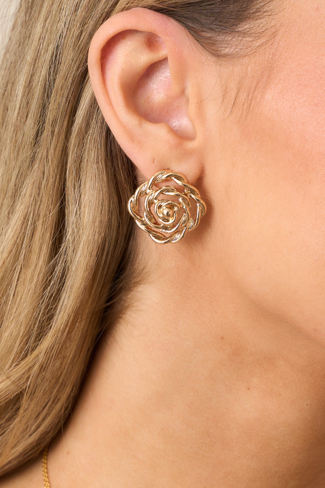 A detailed shot of the gold spiral floral earrings, emphasizing the texture of the hardware and the precise craftsmanship of the design.