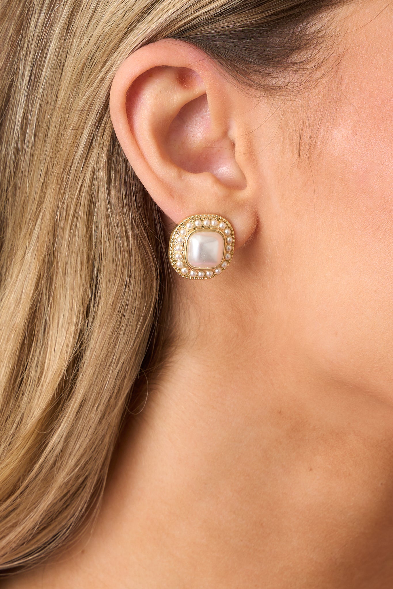 A zoomed-in view of the gold earring, emphasizing the intricate design of the large faux ivory pearl centers, gold borders, and the pearl accents.