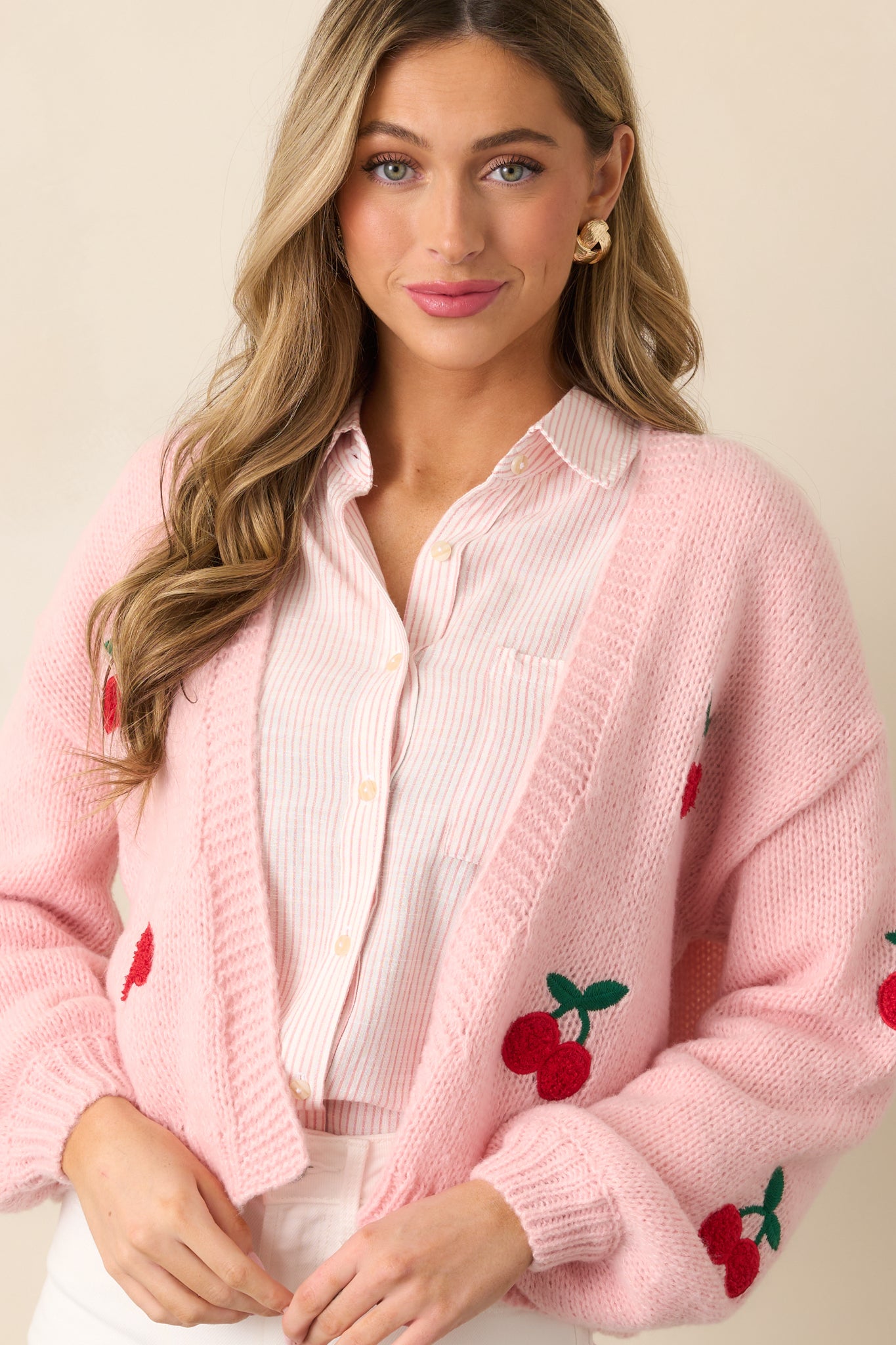 A zoomed-in view of the lower front portion of the cardigan, emphasizing the ribbed hemline and cherry accents.