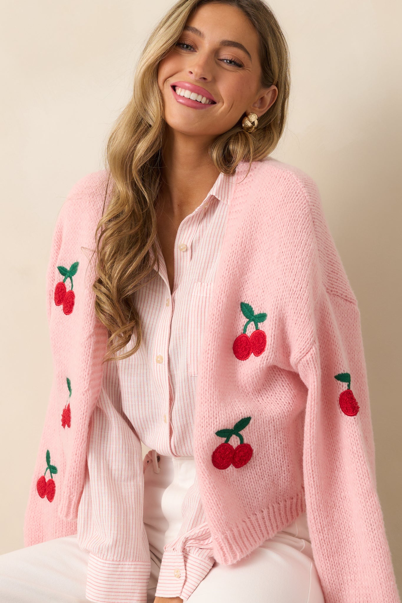 A close-up of the upper front section of the cardigan, showcasing the intricate cherry embroidered decals and ribbed detailing around the neckline.