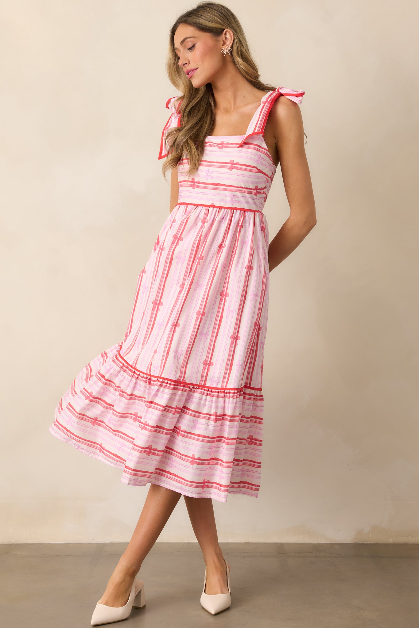 The pink dress viewed from a different angle, highlighting its square neckline, beautiful bow stripe print, and the flow of the tiered skirt.