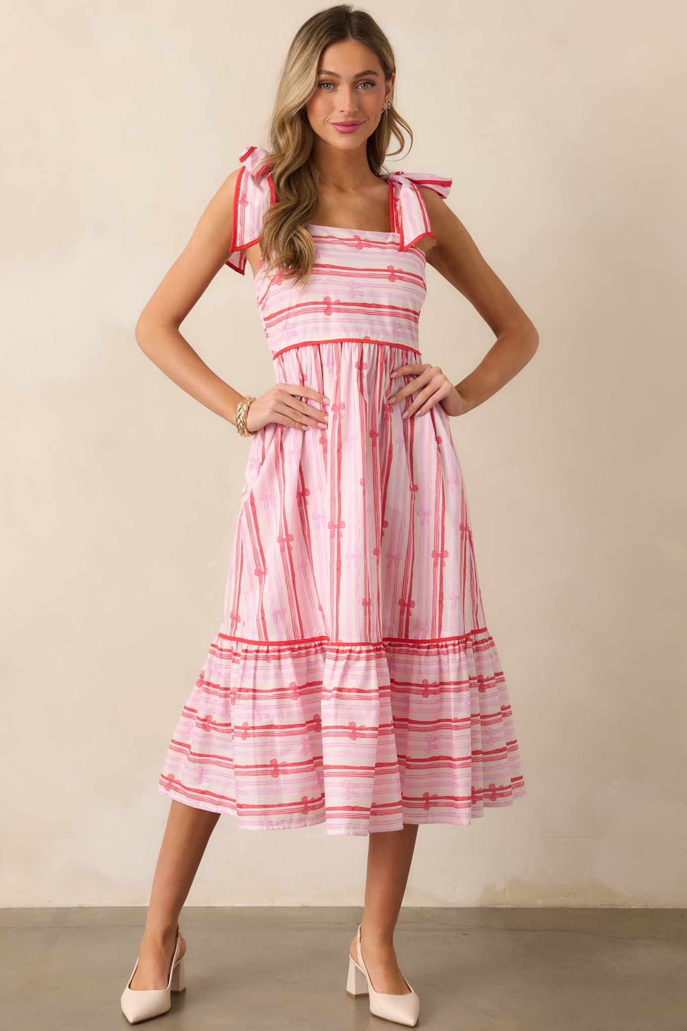 Another front view of the pink dress, emphasizing the smocked back detailing, tiered bottom, and the self-tie shoulder straps.