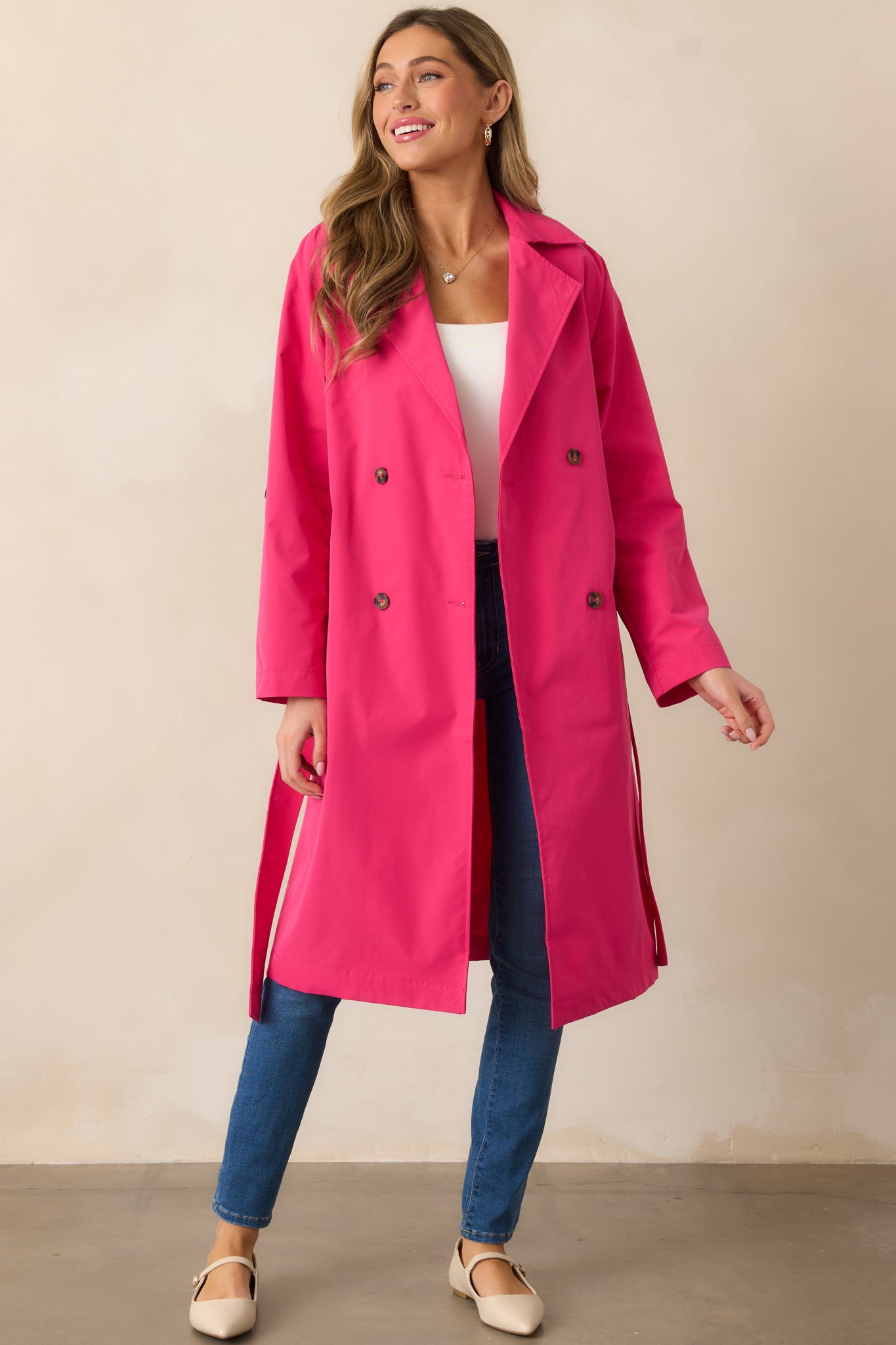 A full-length view of the magenta trench coat featuring its collared neckline and button details, and showcasing the high-quality finish.