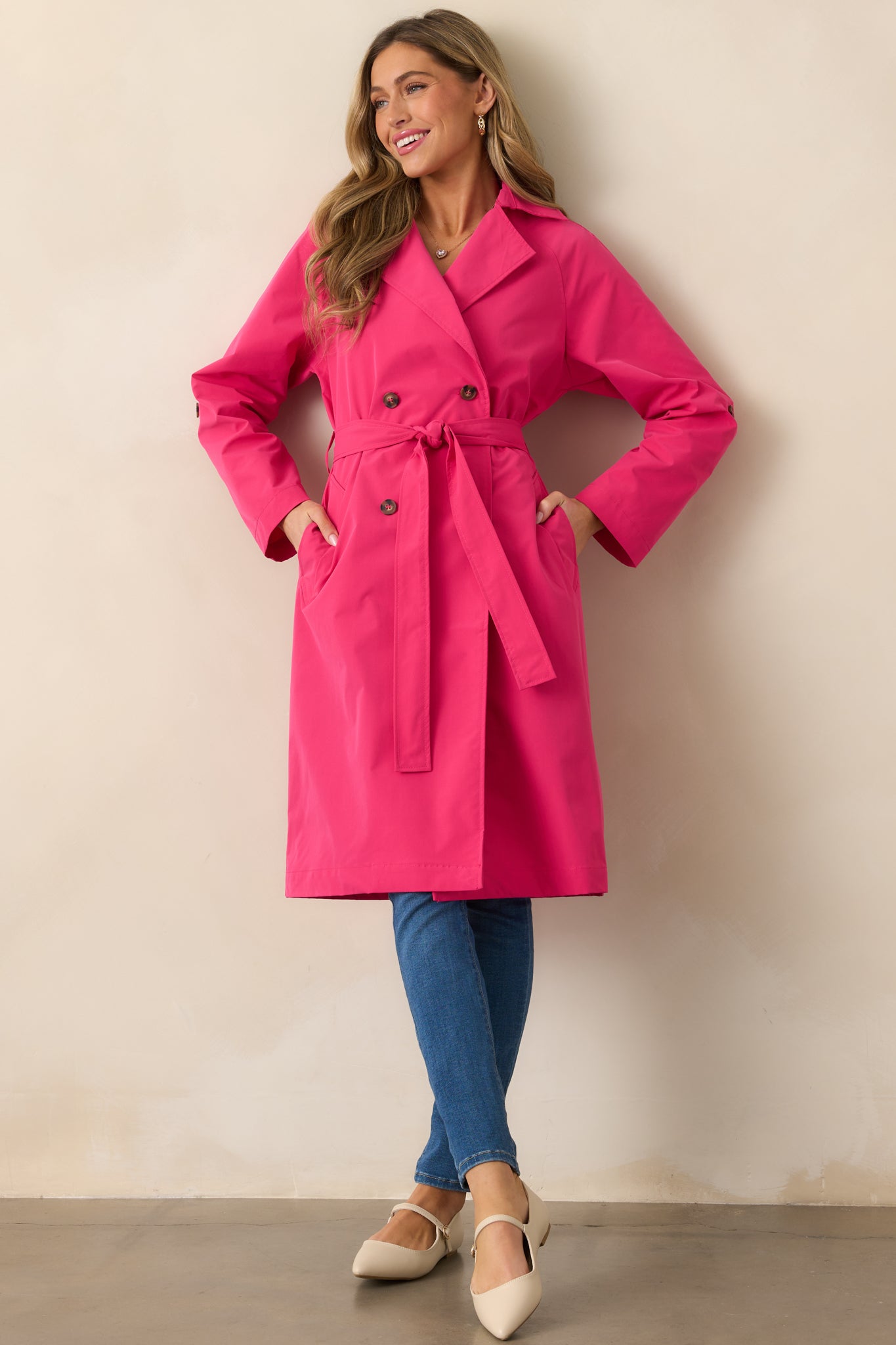 The magenta coat from the front, showcasing its functional button front, double-breasted lapels, and self-tie waistband with a sleek, fitted look.