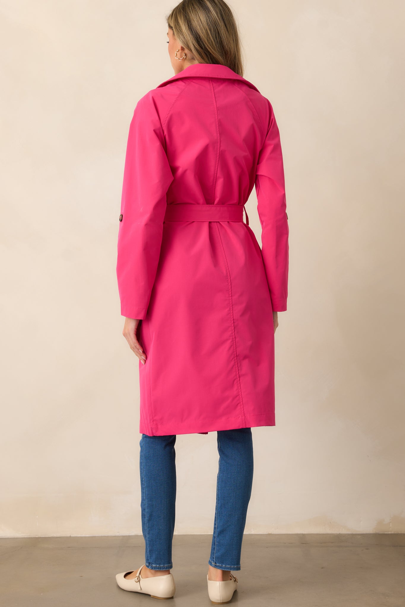 The back view of the magenta coat, showcasing the long sleeves and self-tie waistband cinching the waist for a flattering silhouette.