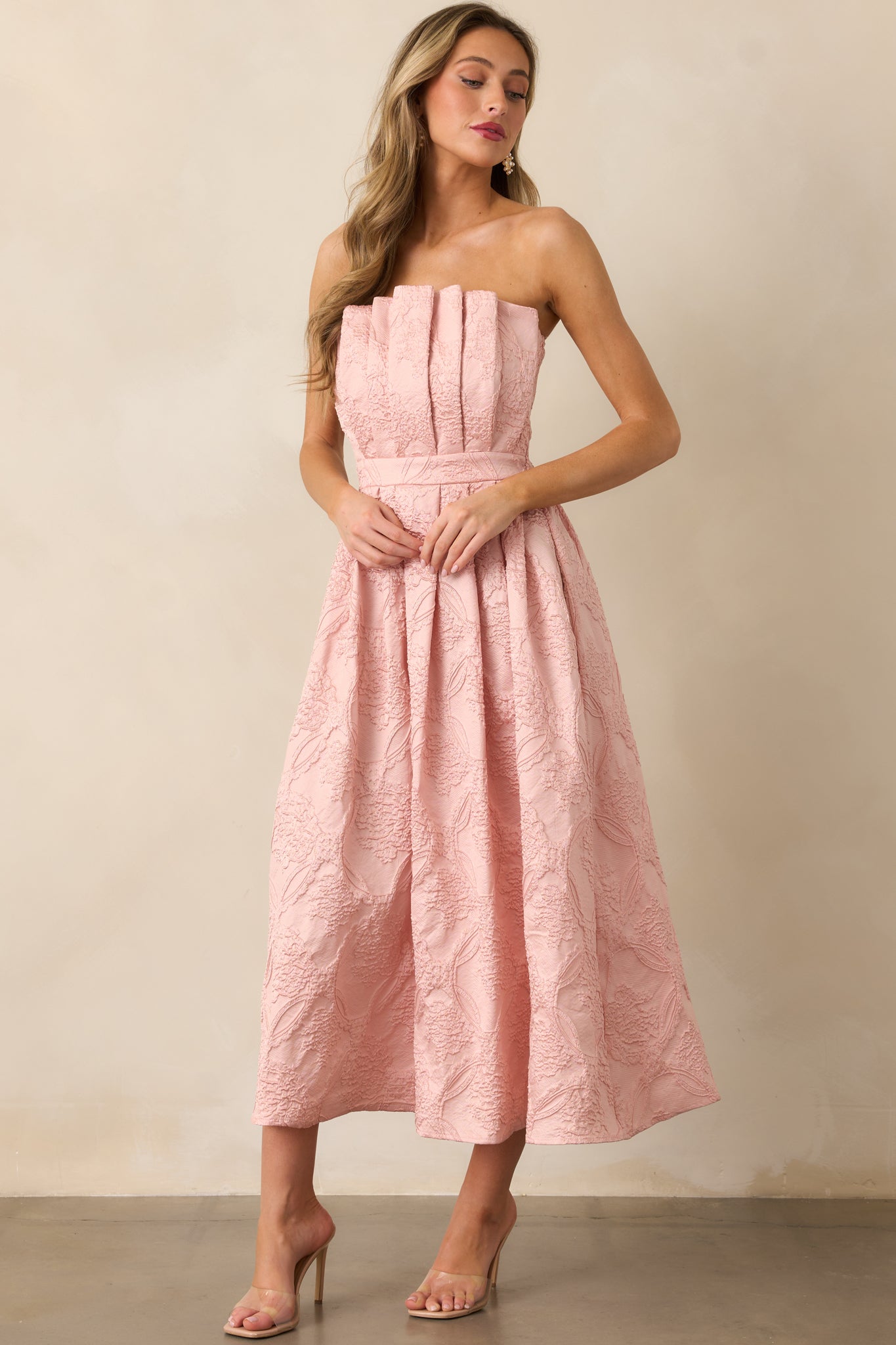 The dress viewed from a different angle, showcasing its strapless design, pleated details, and the flattering silhouette of the skirt.