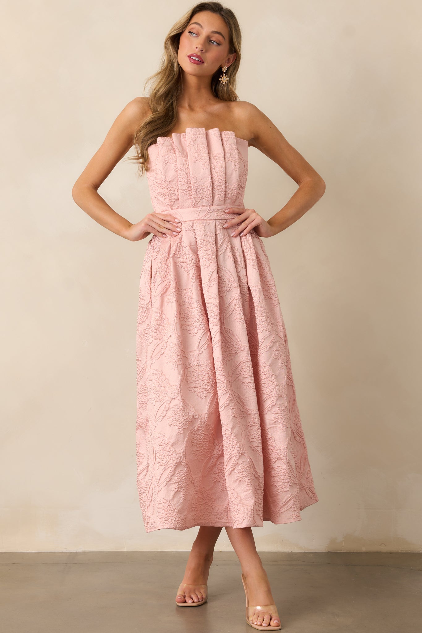 A full view of the blush dress featuring a pleated bodice, slightly pleated skirt, and strapless design, with functional hip pockets and a smocked back.