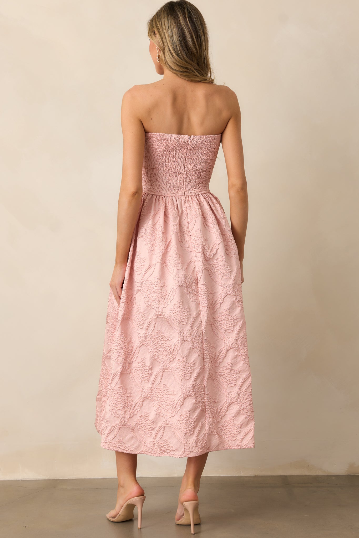 A back view of the blush dress, showing the smocked back and discrete back zipper, with no visible fastenings.