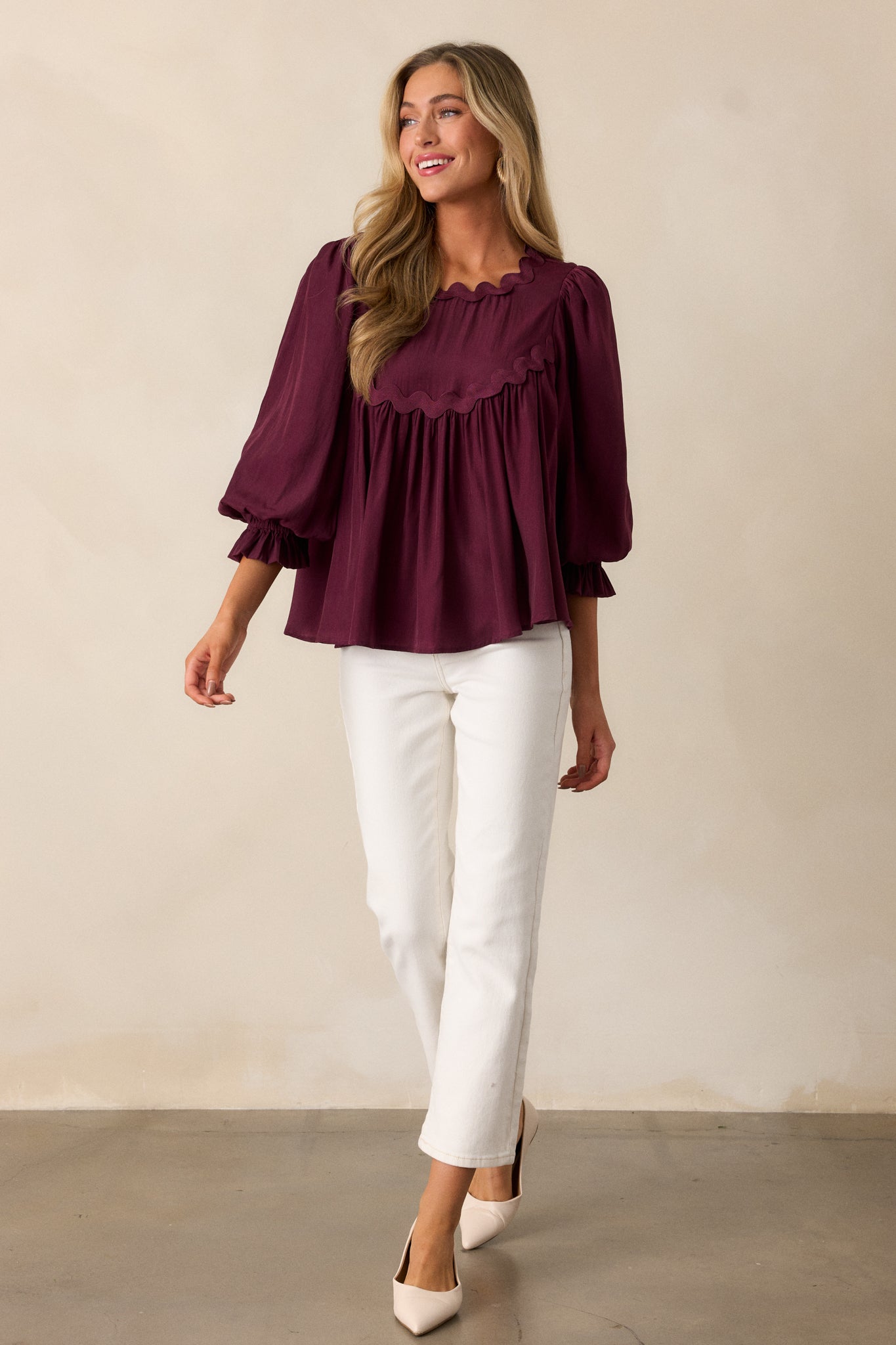 Dark sangria top featuring a scalloped neckline with a single back button, complemented by flowy fabric and 3/4 length poet sleeves.