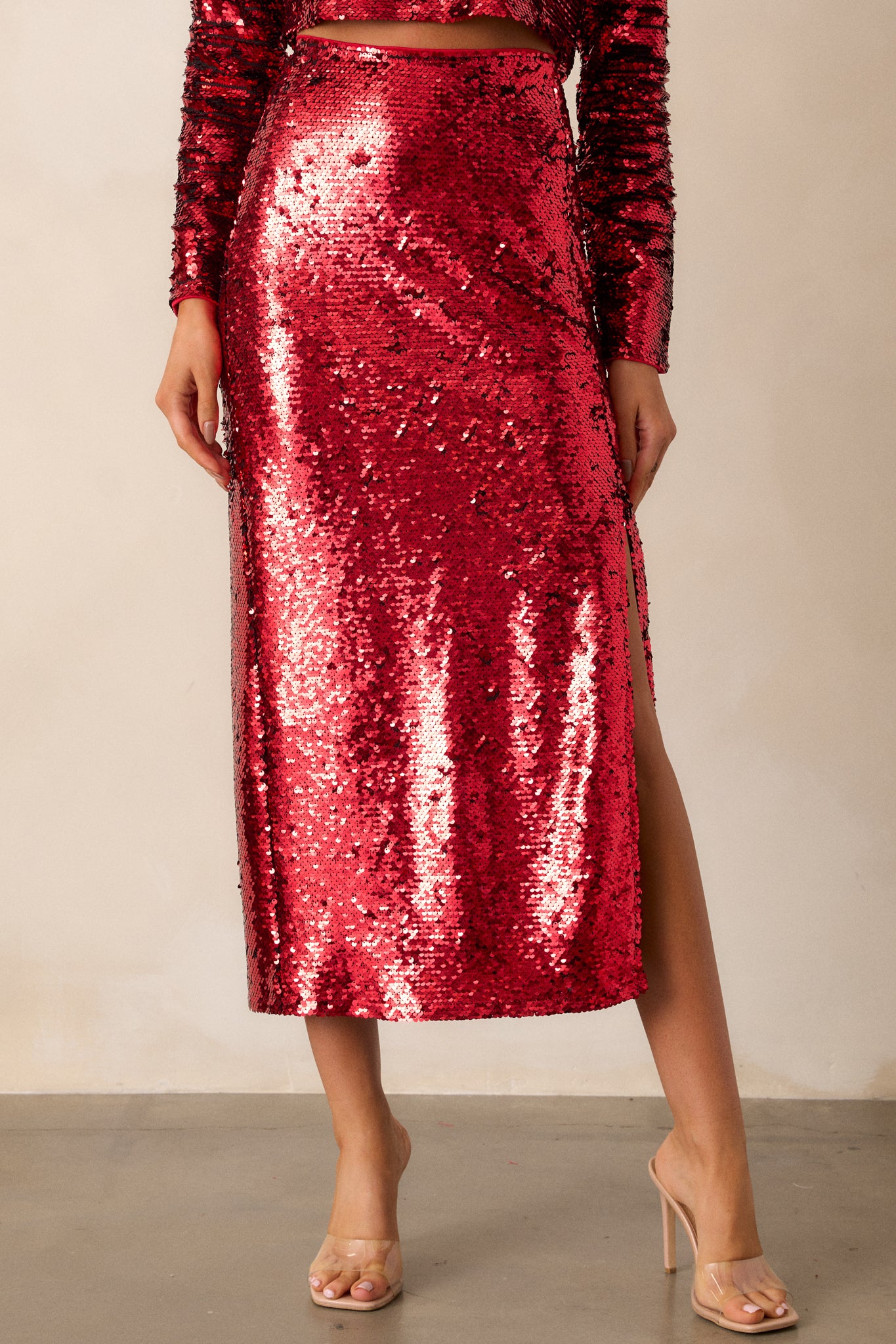 Full body view of this midi skirt that features an all over sequin flip design, a side zipper, and a slit. 