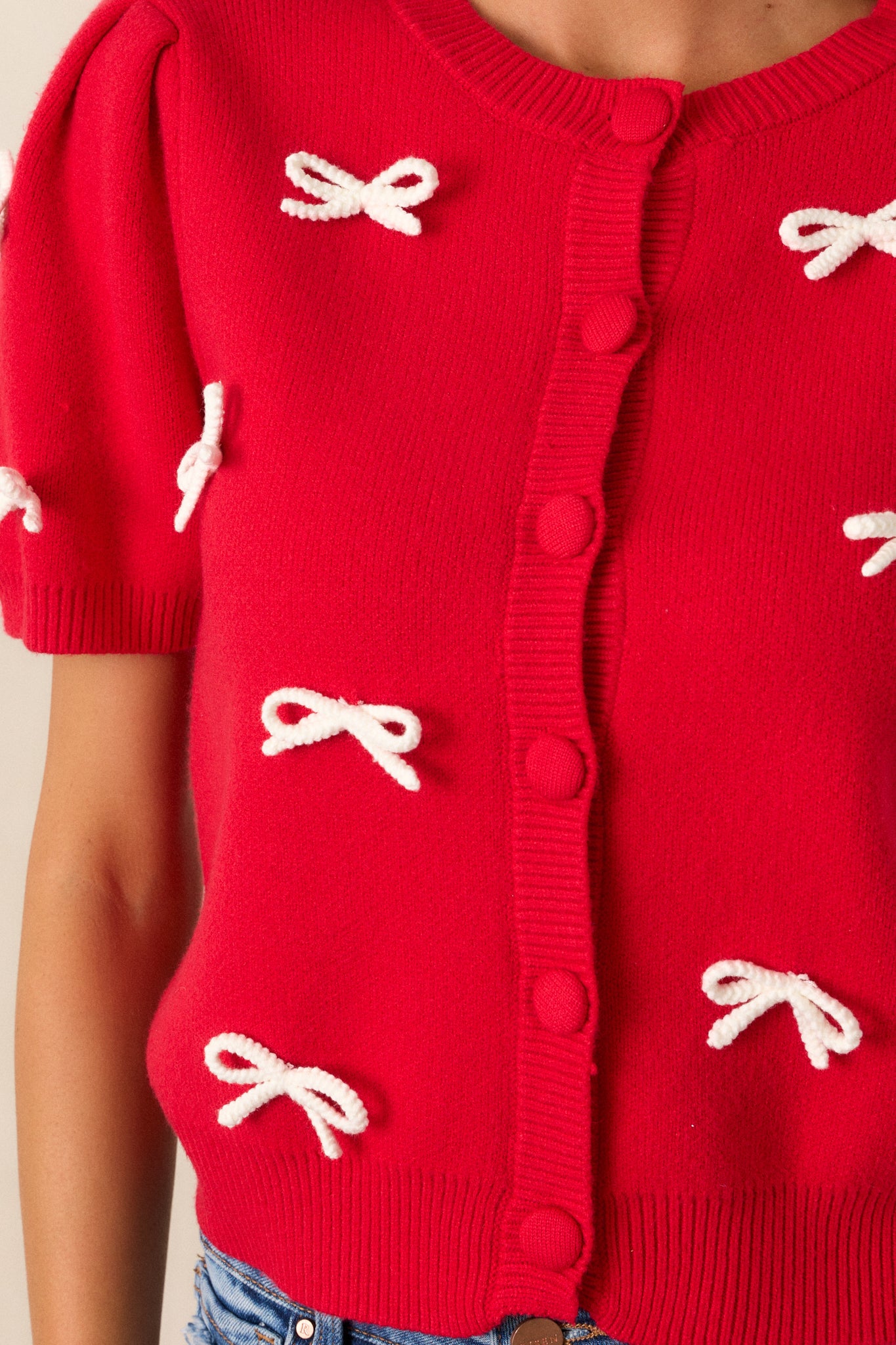 Detailed shot of a knit bow embellishment on the button front, emphasizing the texture of the knit fabric.