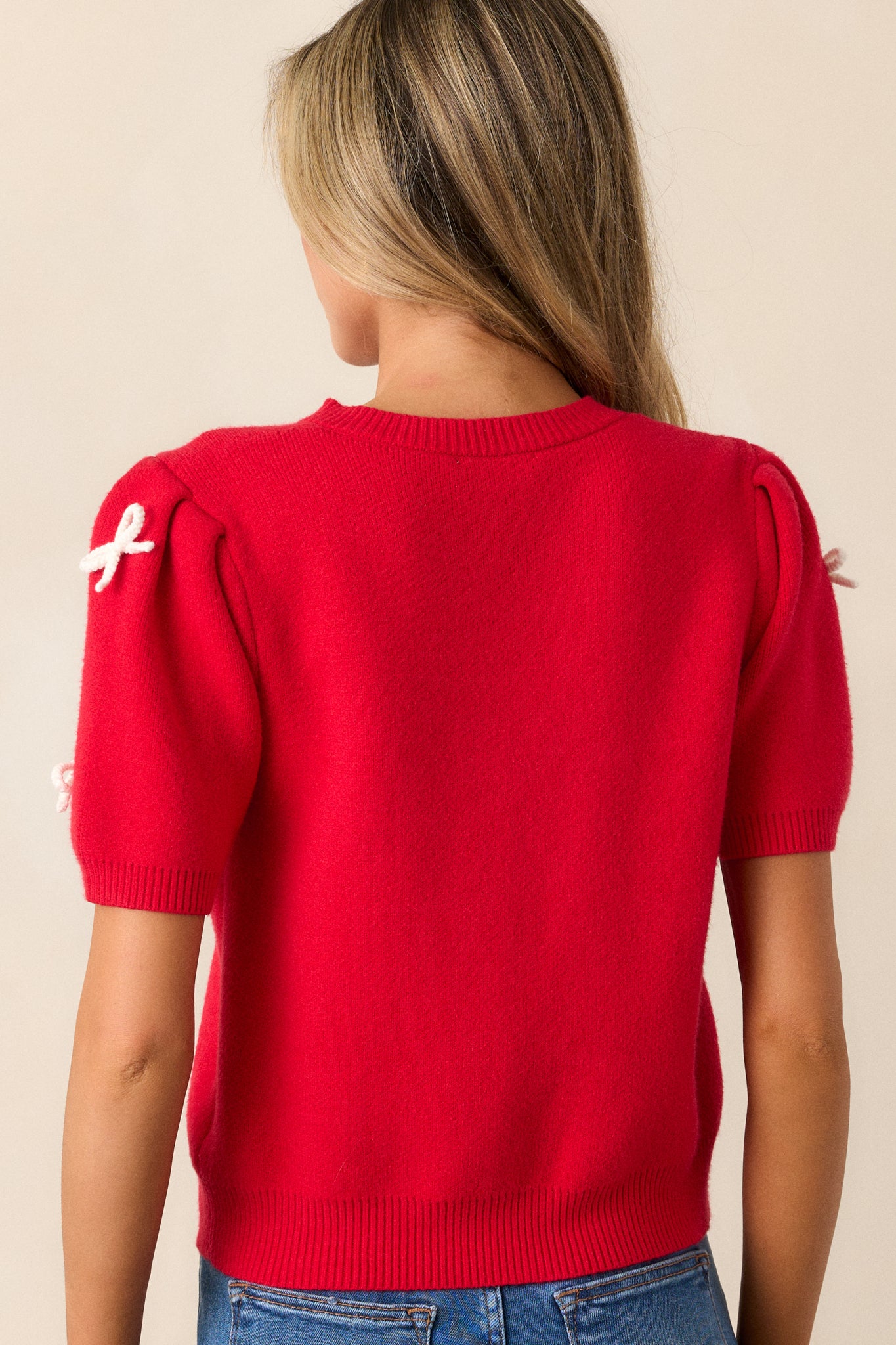 Back view of the red sweater top, displaying the smooth knit back and the shape of the short puff sleeves.