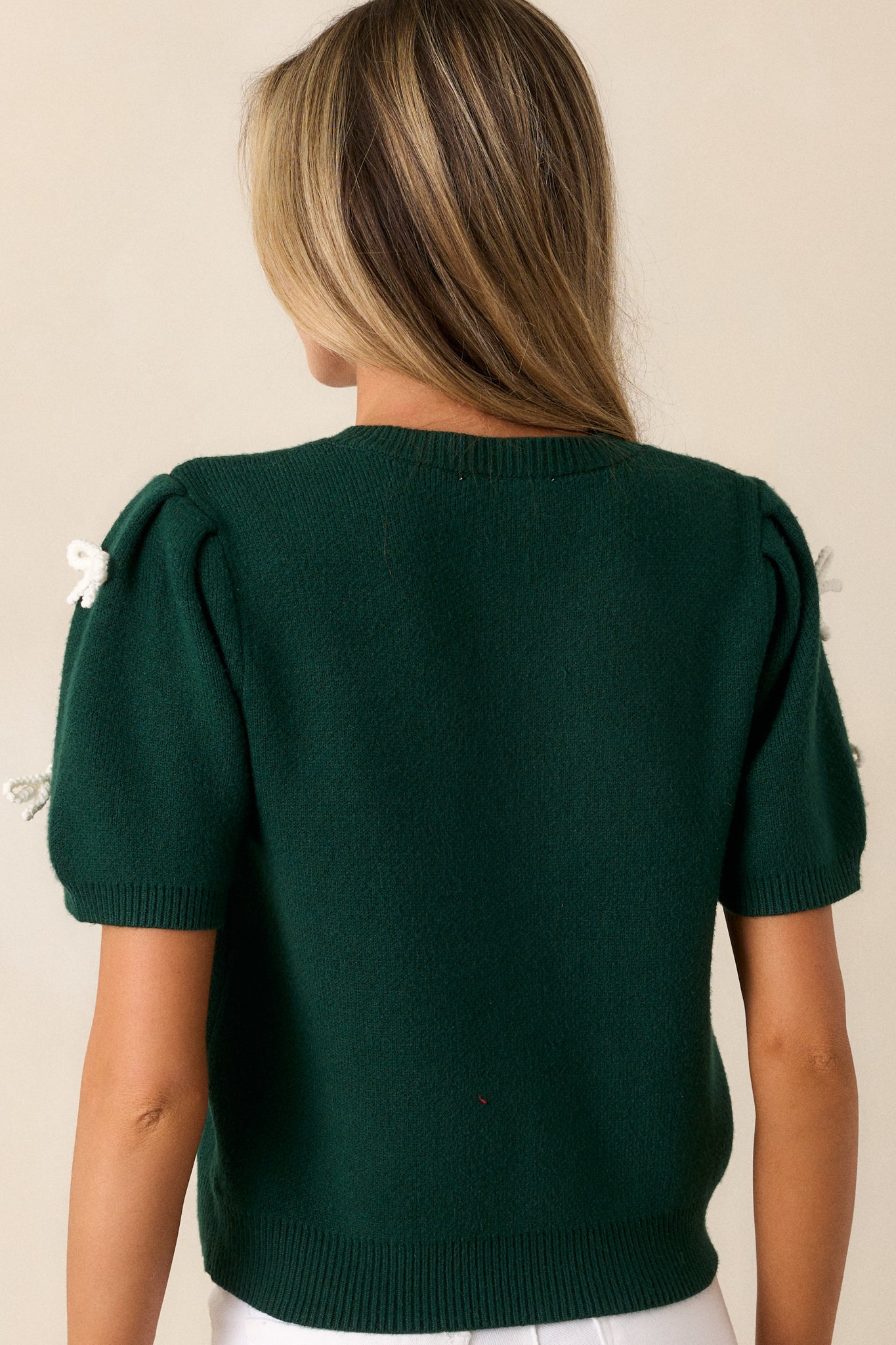 Back view of the green sweater top, displaying the smooth knit back and the shape of the short puff sleeves.