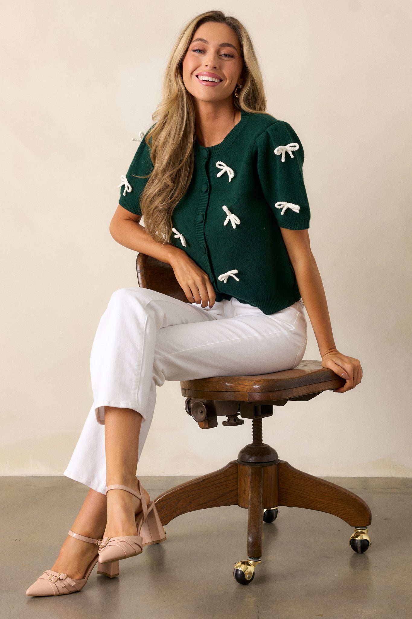 Front view of the green sweater top, showing the rounded crew neckline, button front, and short puff sleeves with ribbed cuffs.