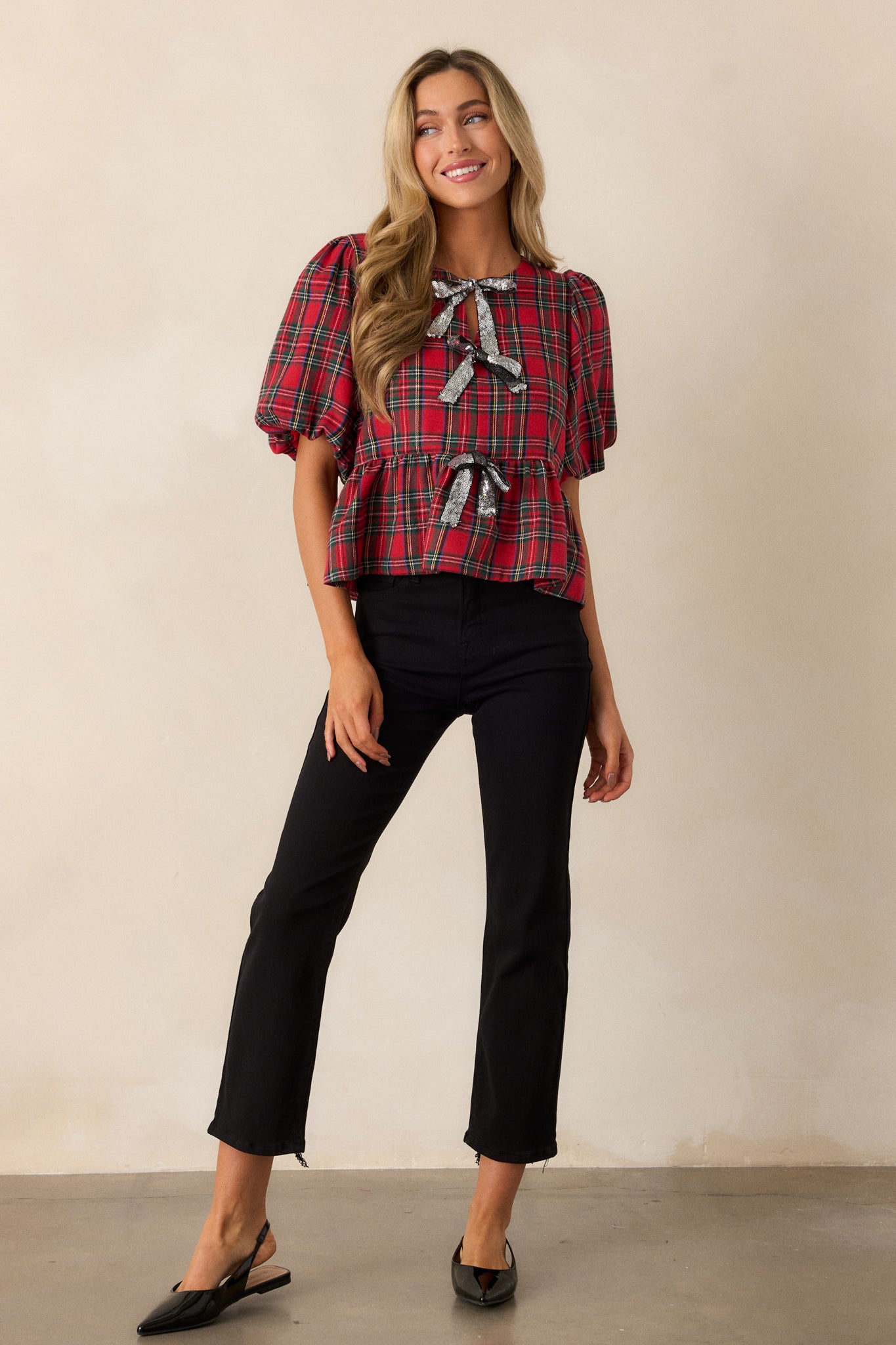 Full view of the red top featuring a high neckline and short puffer sleeves, showcasing the vibrant red and black plaid design.
