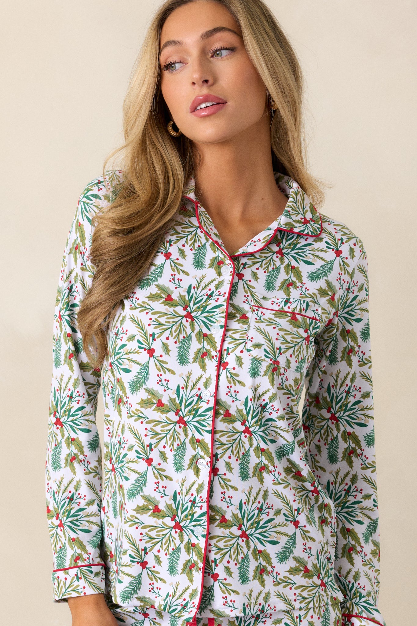 Focused look at red-trimmed sleeve cuff and mistletoe print on soft ivory pajama top.