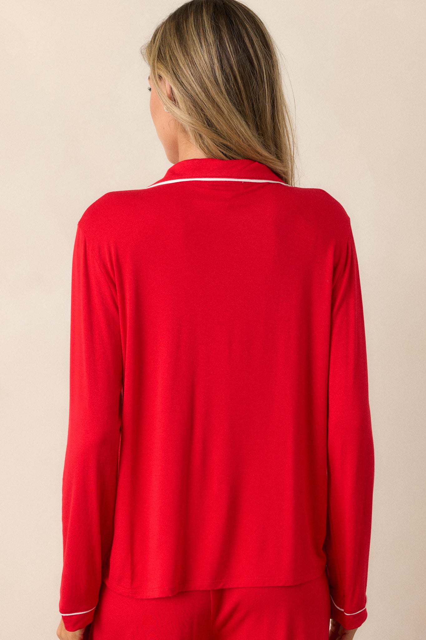 View of the back of the pajama top, highlighting the smooth red fabric and the relaxed fit, with no trim detailing on the back panel.