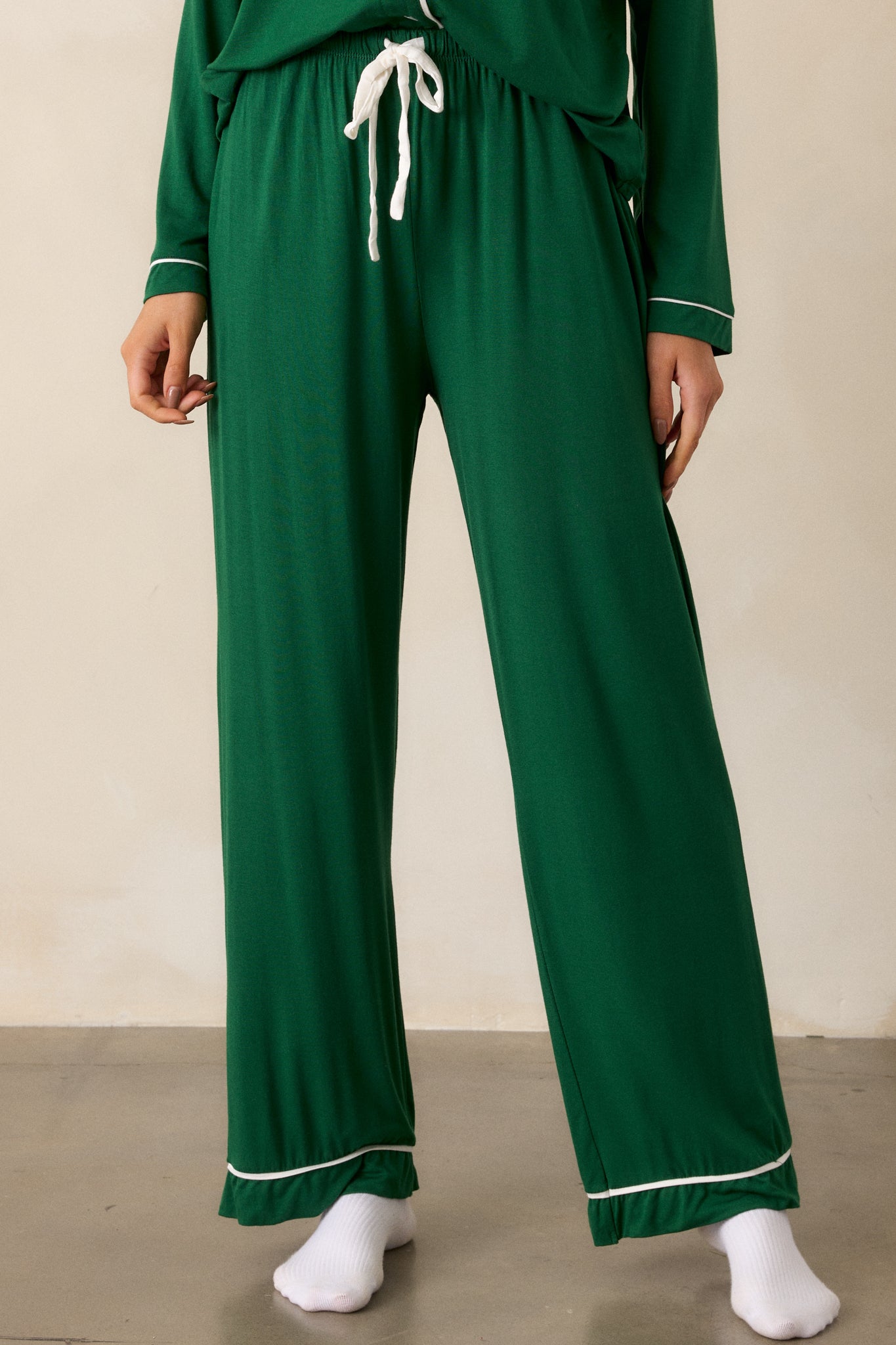 Front view of forest green Pajama Pants featuring an elastic drawstring waistband with a white string, white trim detailing and long relaxed pant legs.