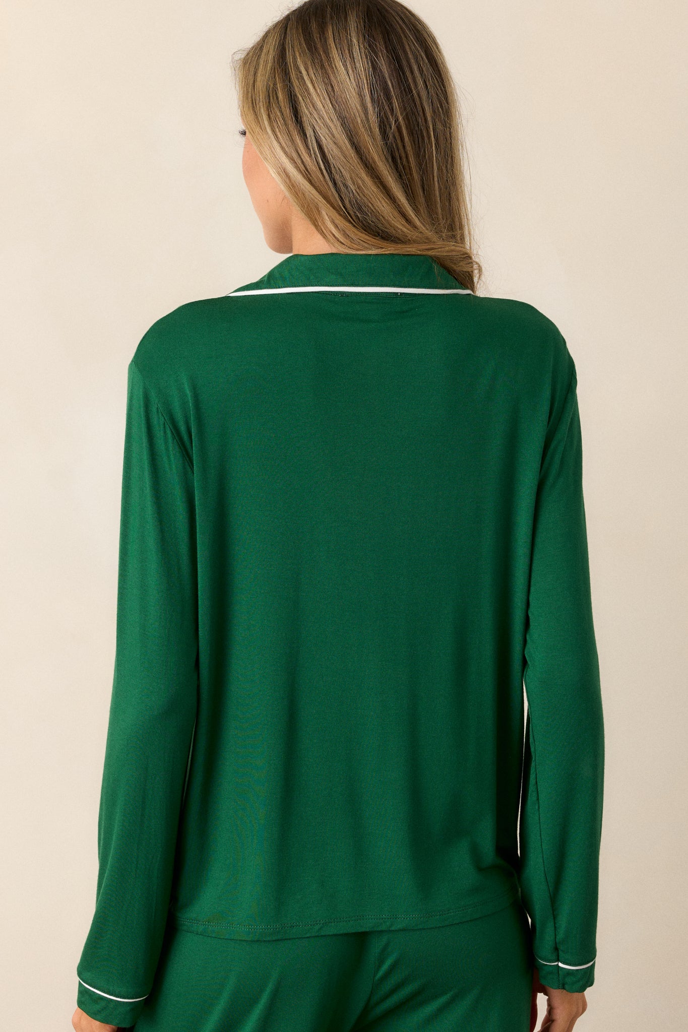 View of the back of the pajama top, highlighting the smooth green fabric and the relaxed fit, with no trim detailing on the back panel.