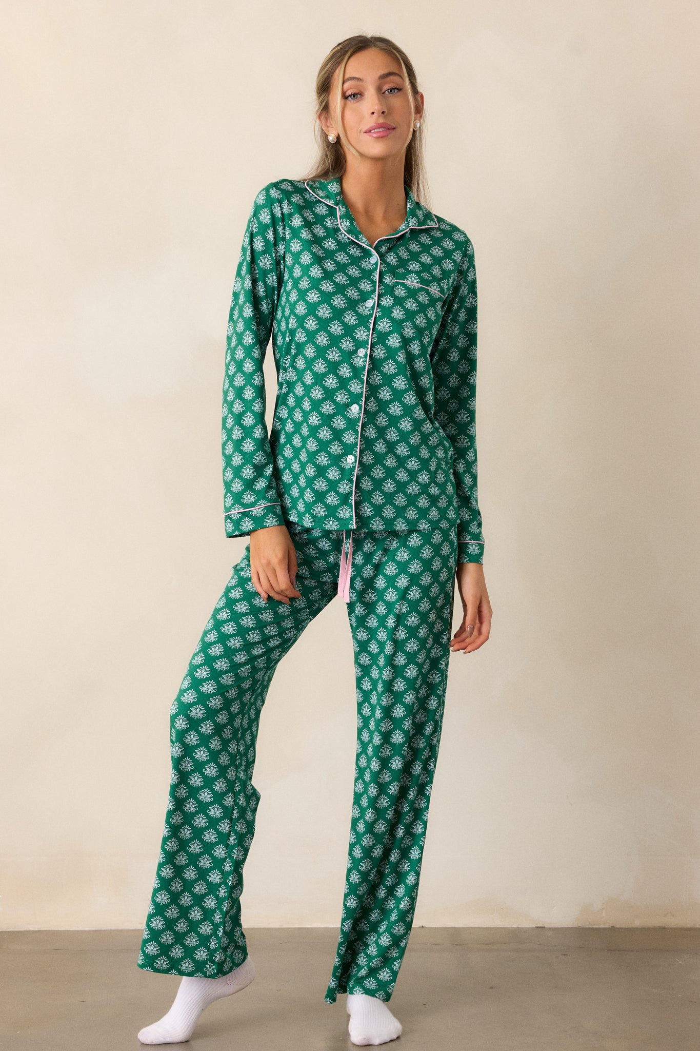 The pajama pants displayed from the front, showcasing the soft green fabric, pink tie at the waistband, and the intricate Fleur de Lis pattern throughout the legs.