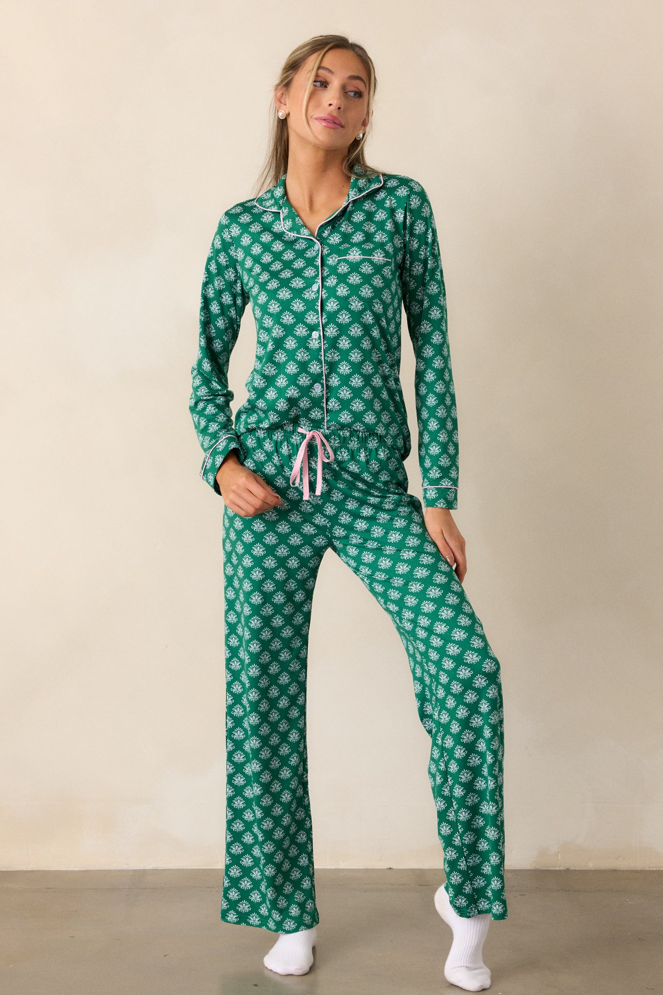 A full view of the green pajama pants, highlighting the elastic waistband with a pink tie and the Fleur de Lis pattern along the relaxed fit legs.