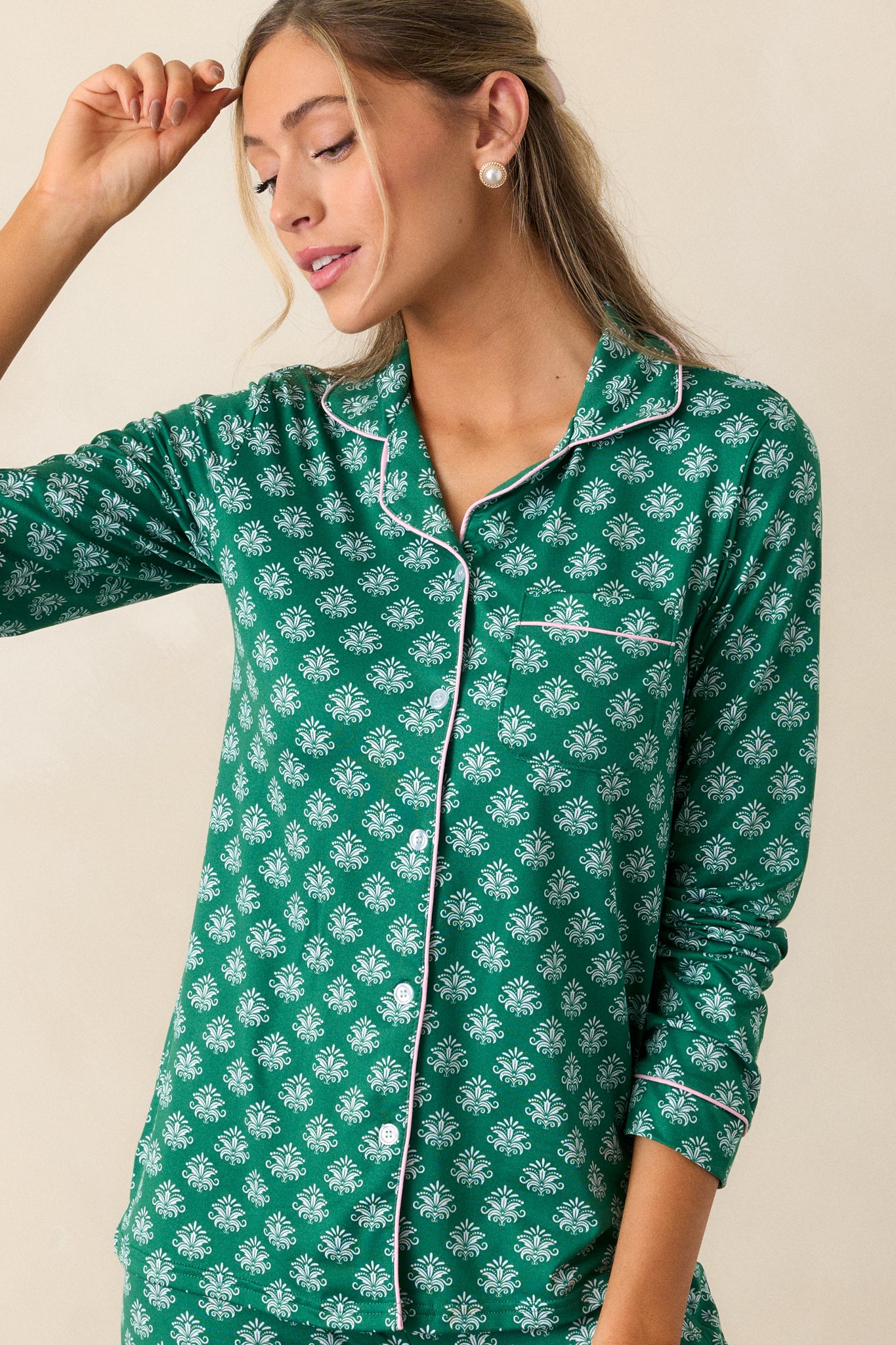 Focused look at the long sleeve with pink-trimmed cuff and Fleur de Lis pattern on green pajama top.