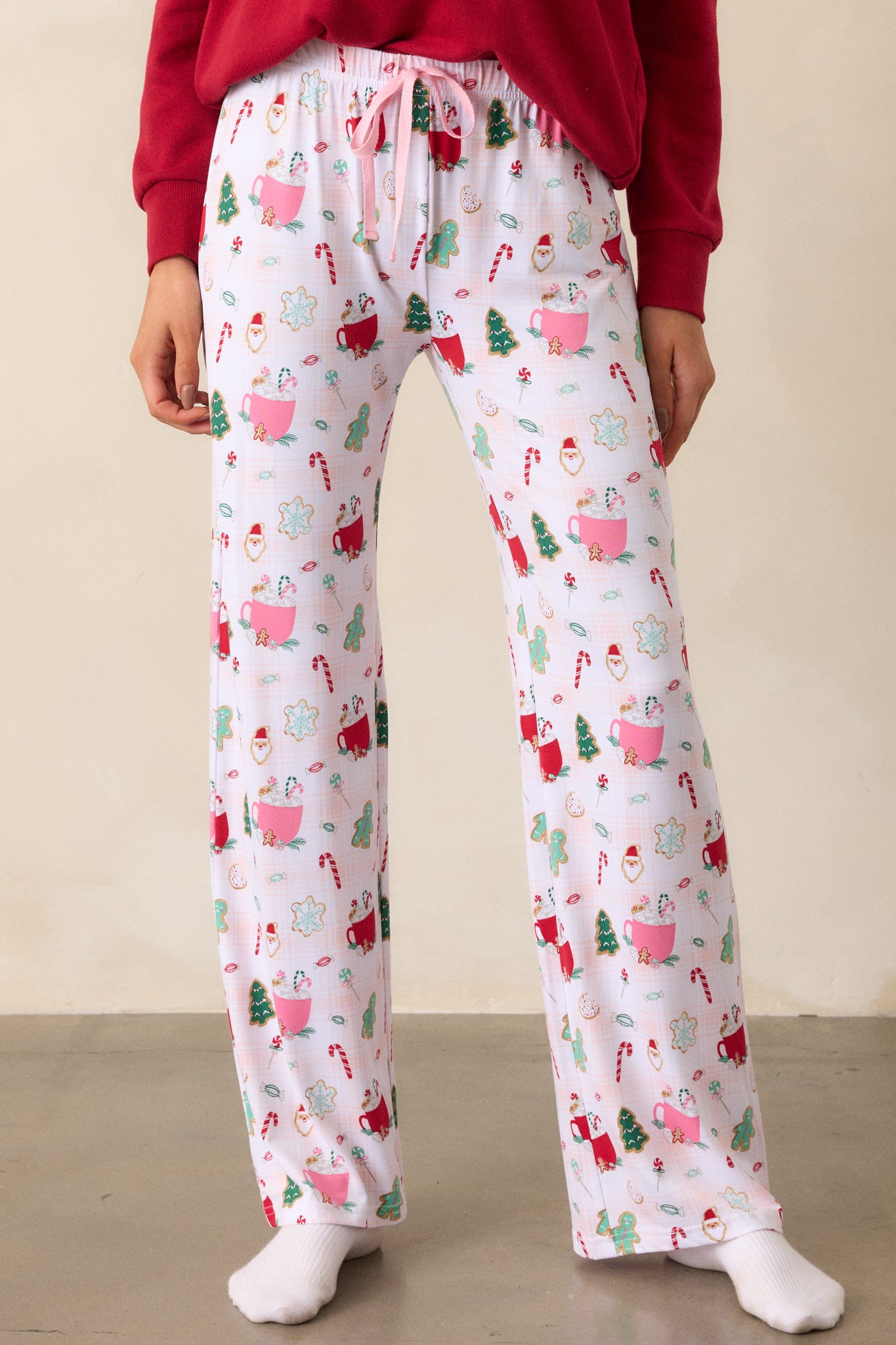 A front view of the pajama pants, emphasizing the vibrant holiday print and the pink drawstring at the waistband, with the relaxed fit of the long pant legs.