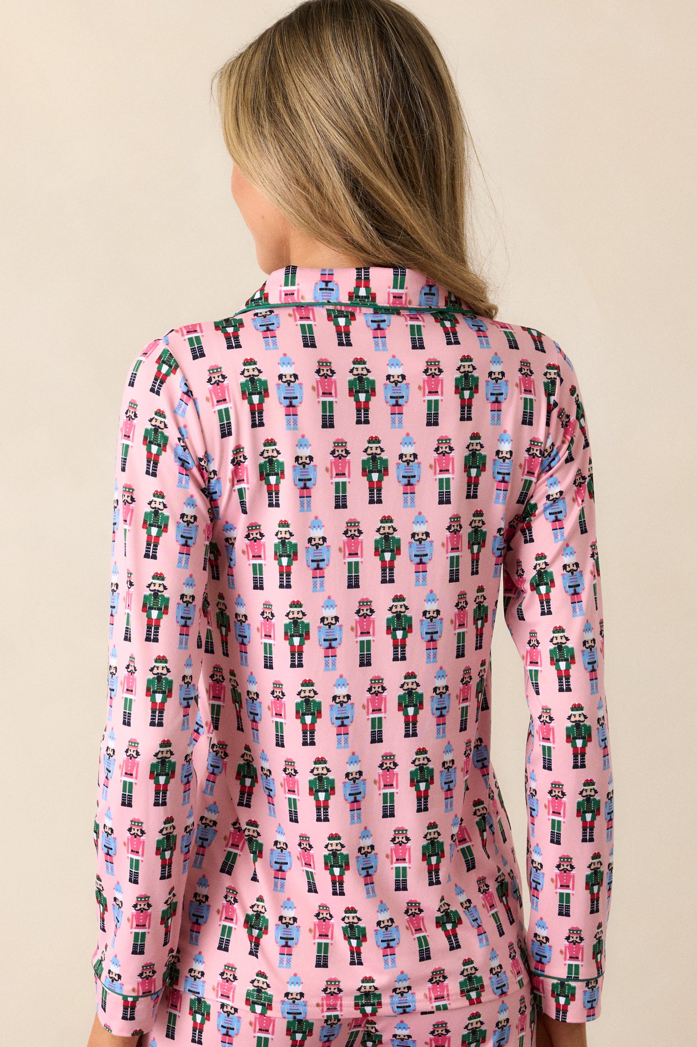 Back view of the pink pajama top with nutcracker print and green-trimmed cuffs, featuring a relaxed fit and long sleeves.