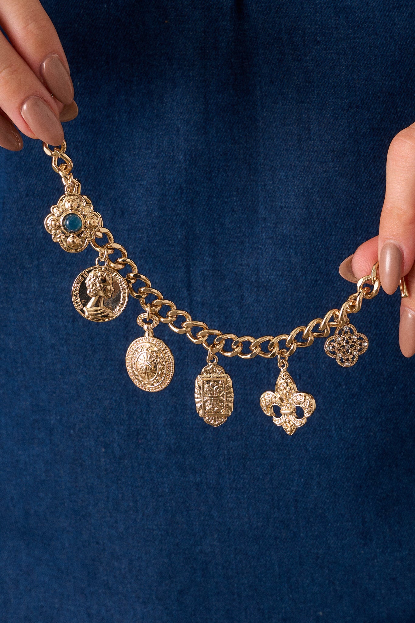 A side angle of the bracelet, emphasizing the toggle clasp closure and how it secures the bracelet, along with the varied shapes of the gold pendants.