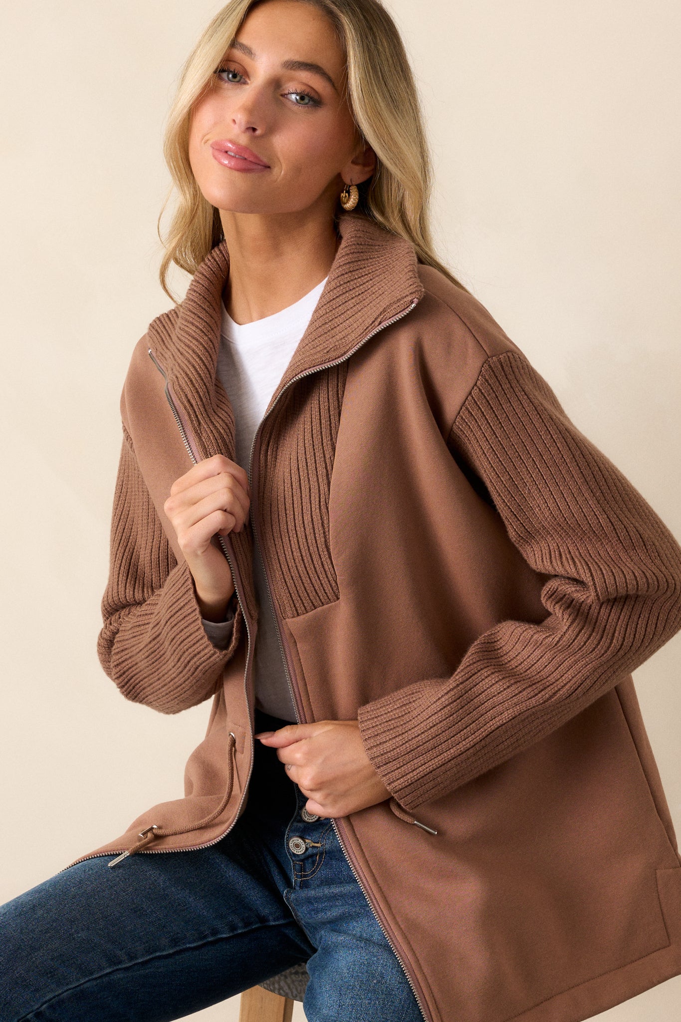 A cropped view of the upper portion of the jacket, focusing on the knit high neck, contrasting fabrics, and the zipper closure.