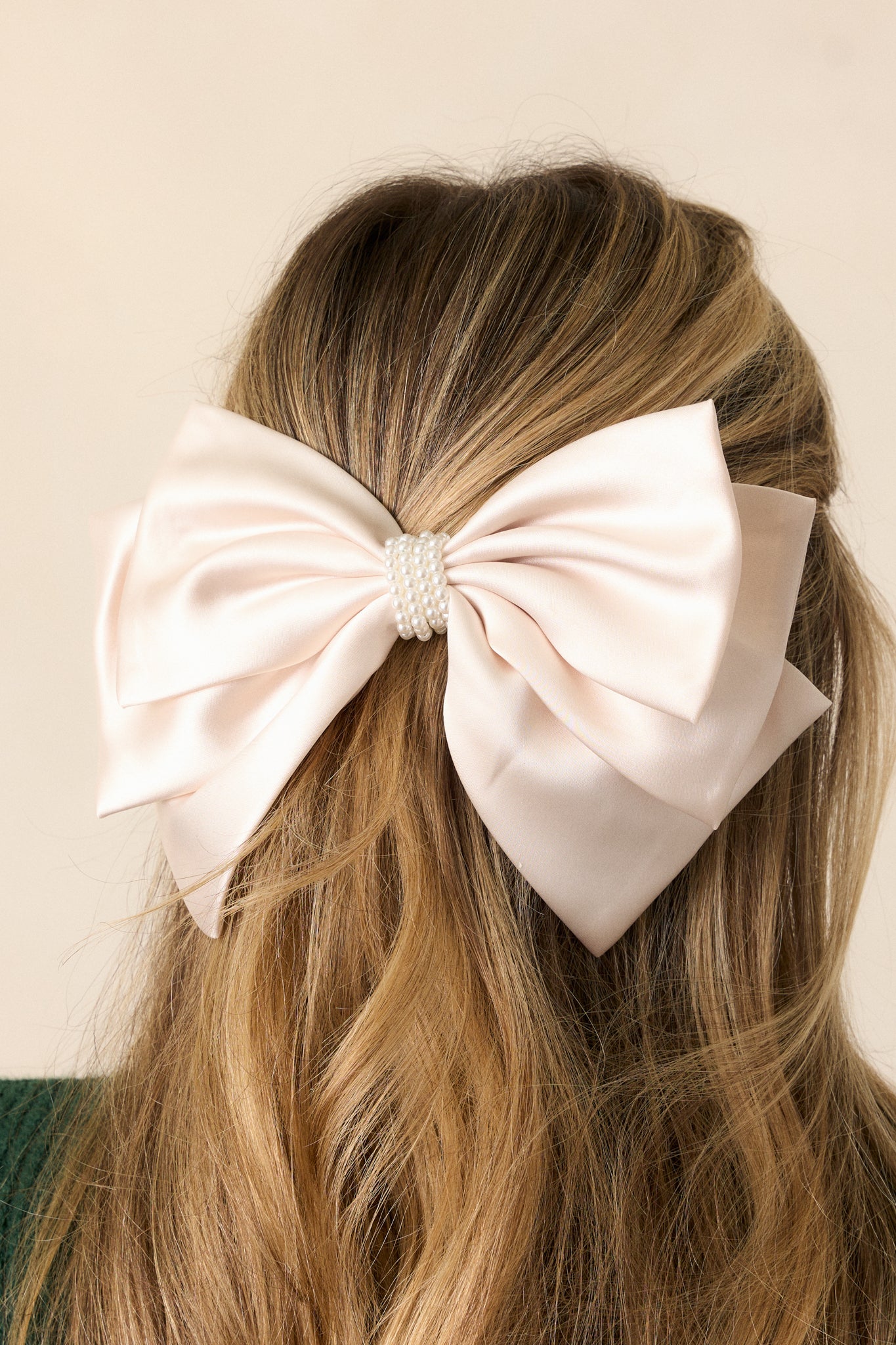 A close-up of the pearl center, capturing its lustrous finish, and the intricate layering of the ivory fabric that enhances the bow's overall charm.