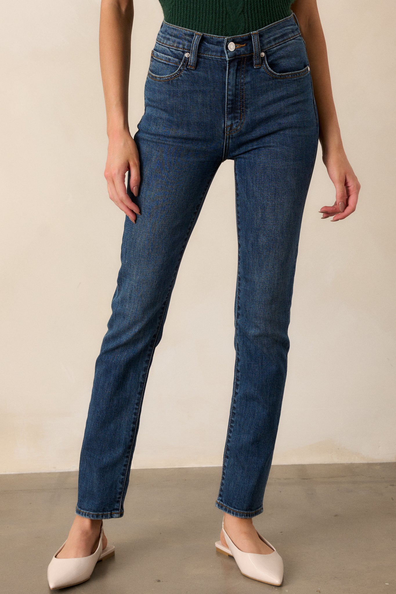 A cropped view focusing on the waistband of the dark wash jeans, highlighting the functional belt loops and the zipper button front closure