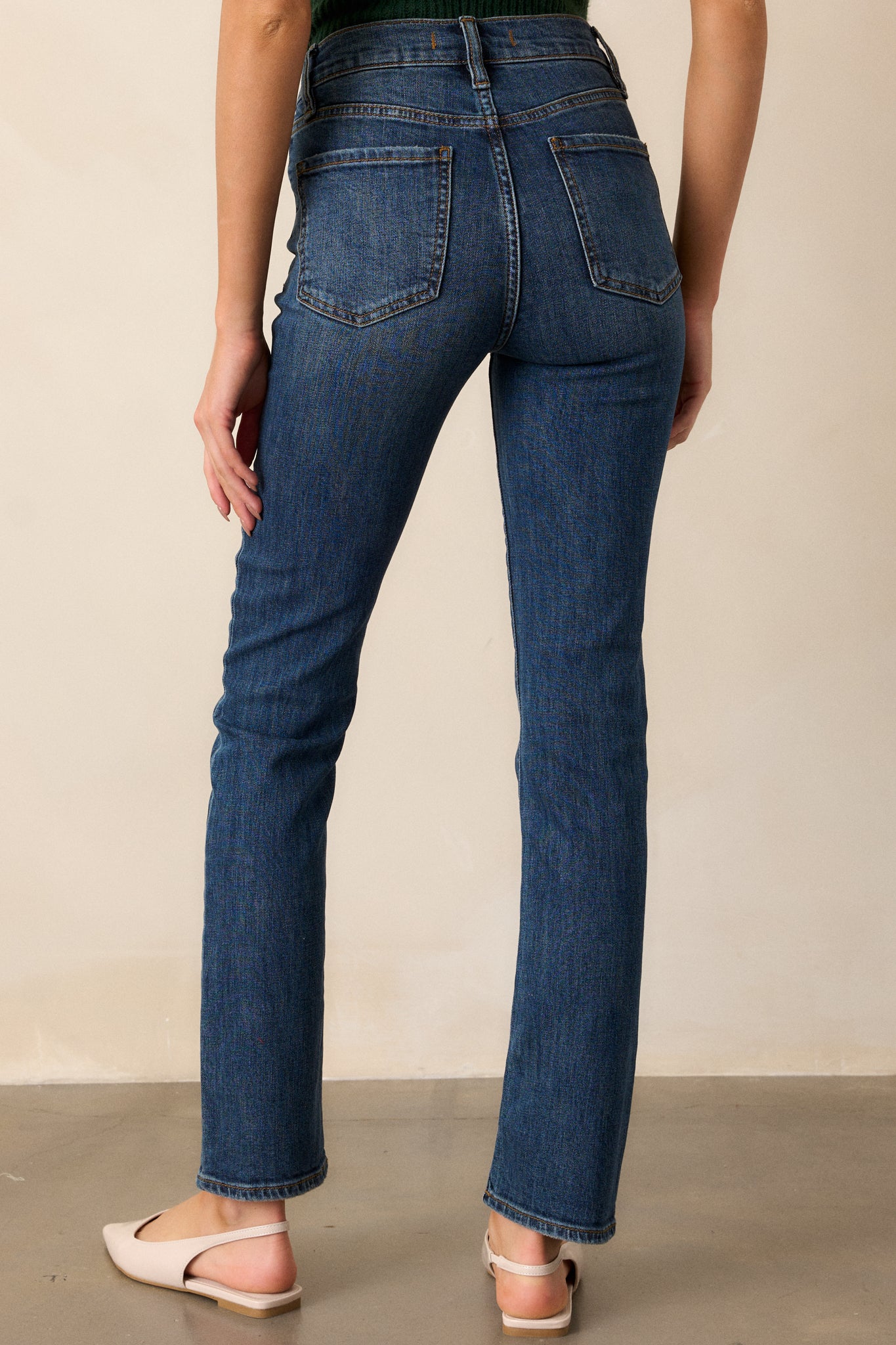 A back view of the dark wash jeans, showcasing the pocket placement, straight leg fit, and the overall sleek design.