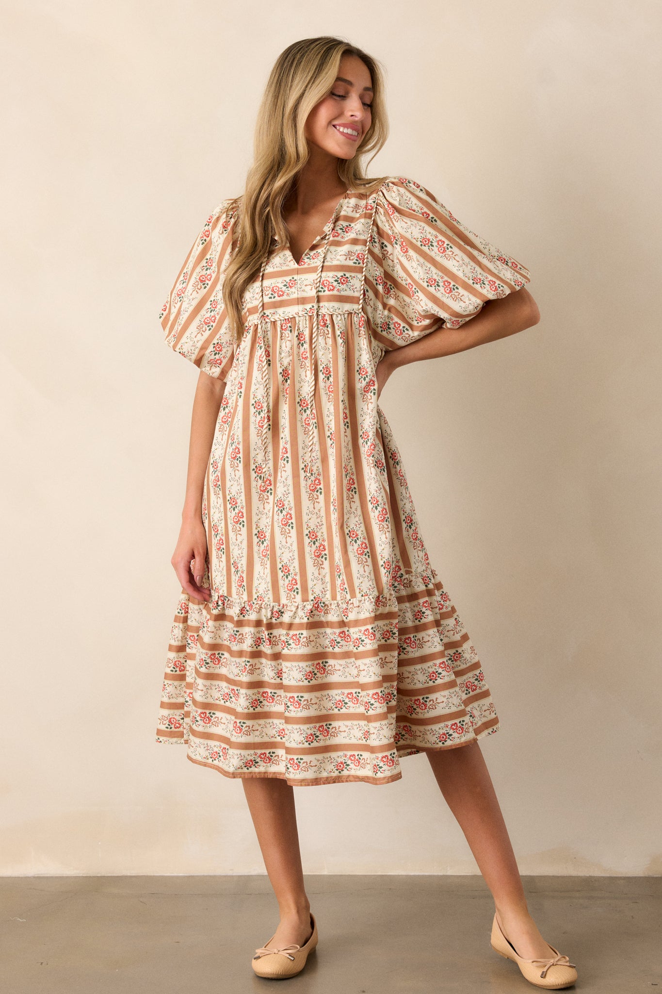 A full-length view of the camel dress, highlighting its midi length and mix-matched stripe and floral pattern.